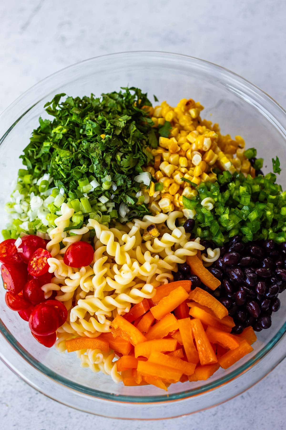 Southwest pasta salad ingredients in a bowl ready to toss.