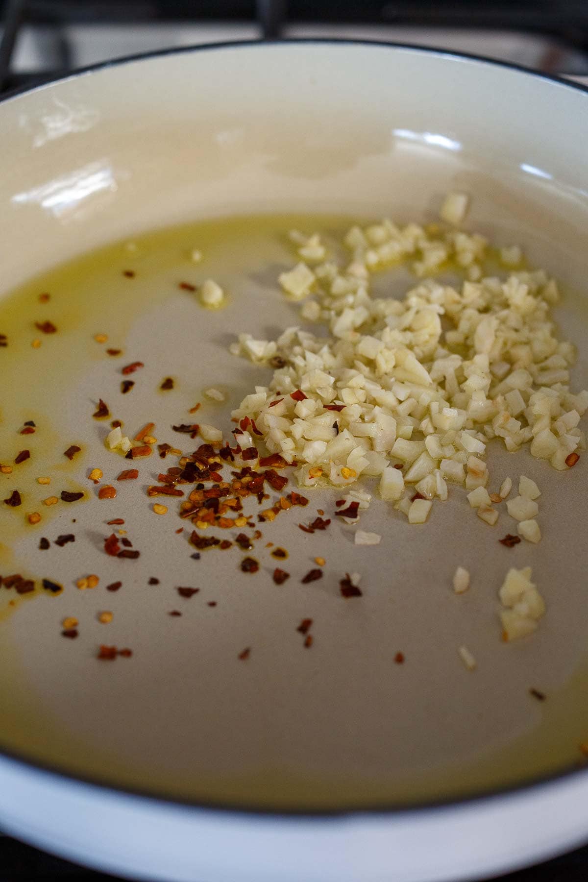 Garlic, red pepper flakes and olive oil in a pan for stuffed zucchini.