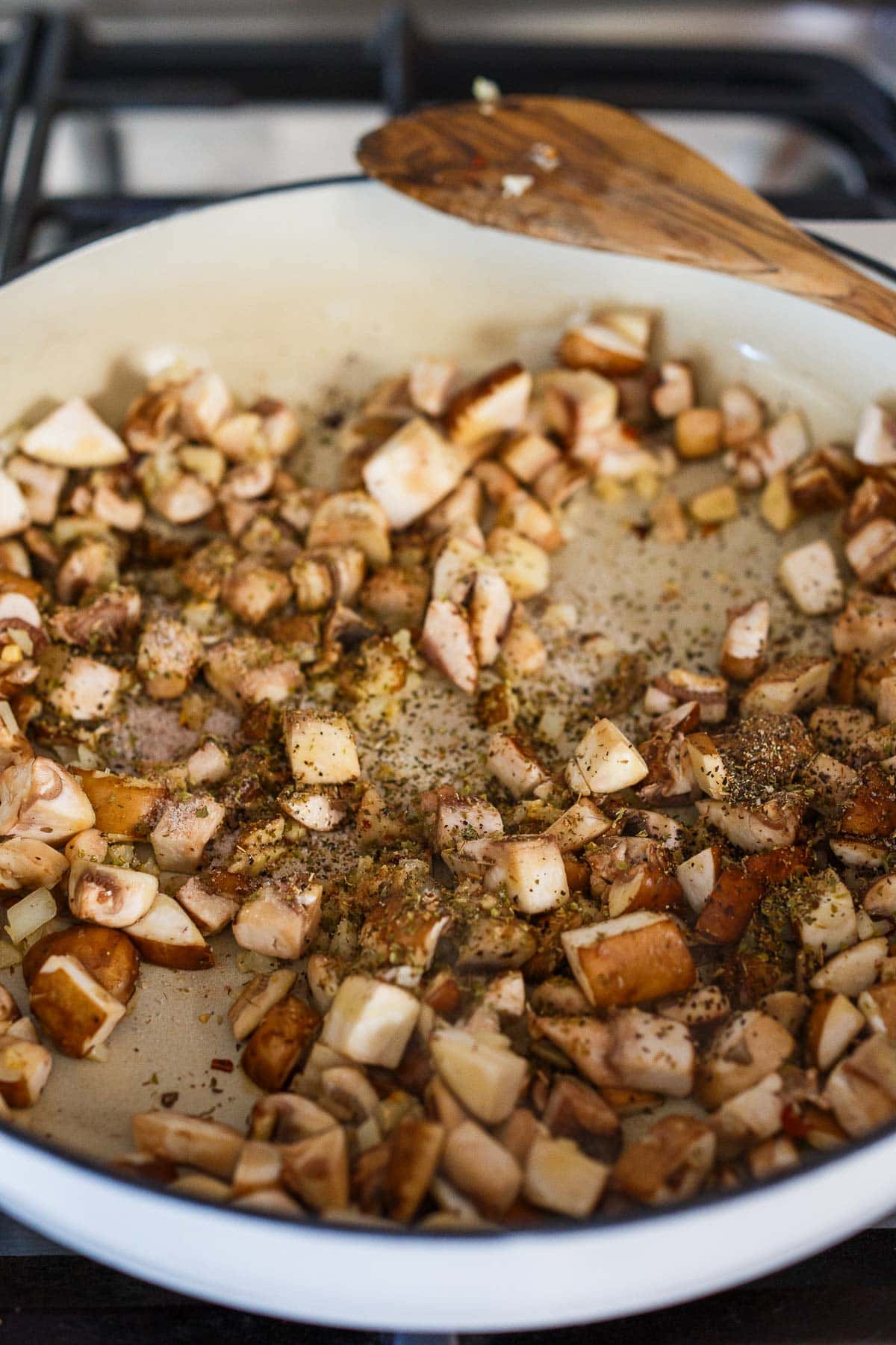 Mushrooms and zucchini sauteing in a pan for Stuffed Zucchini.