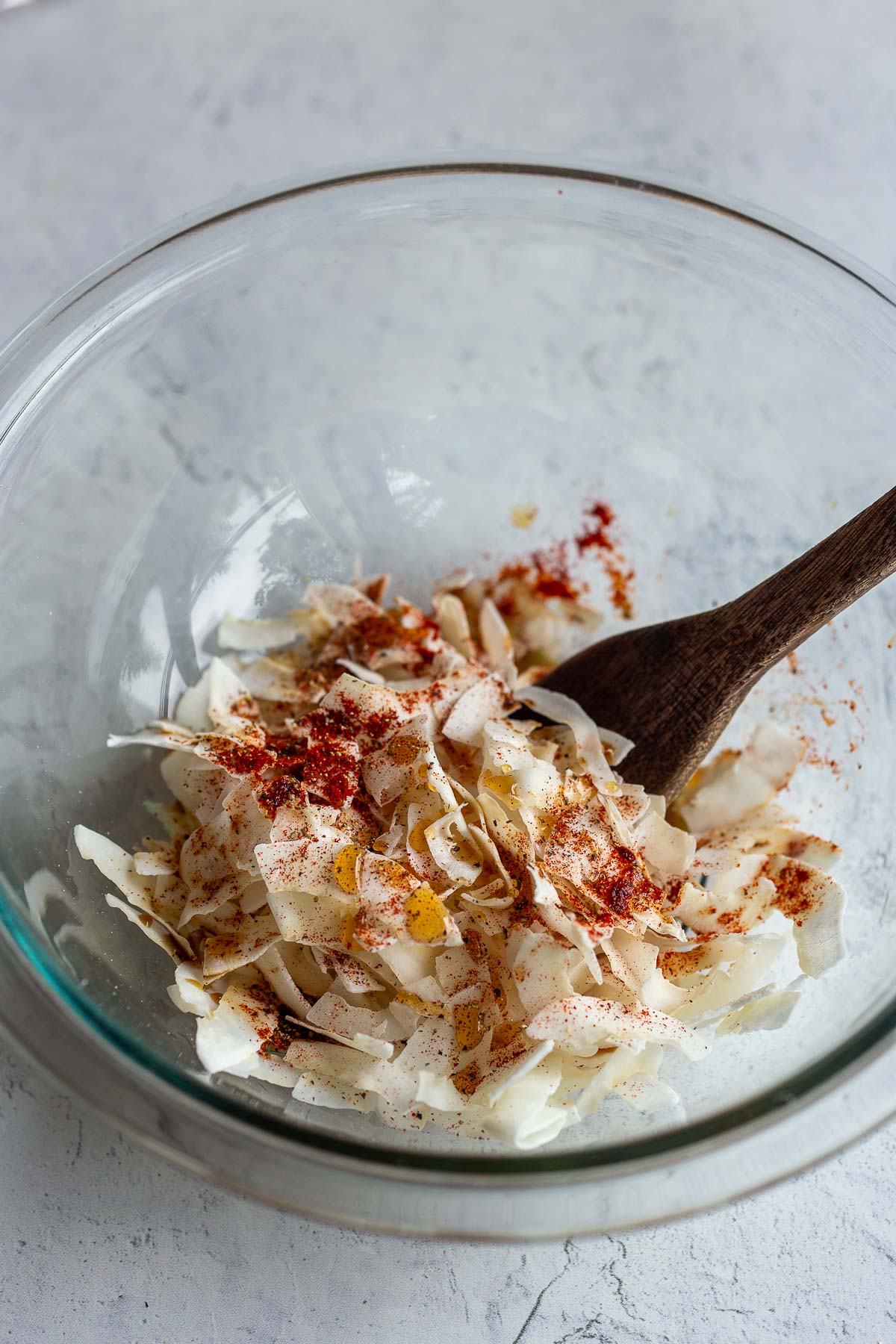 Stirring coconut flakes and seasonings in a bowl for coconut bacon.