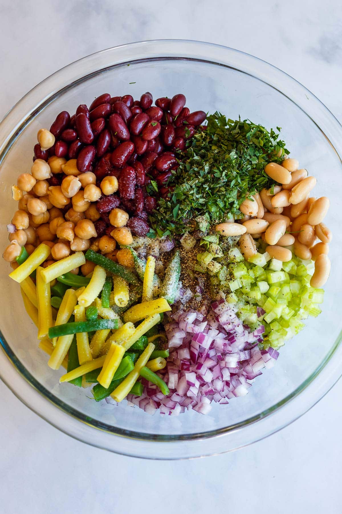 Ingredients for three bean salad ready to toss in a bowl.