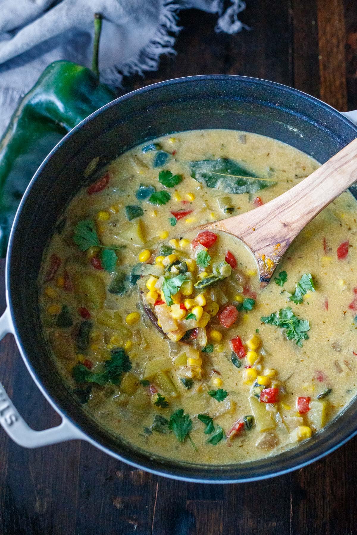 soup pot with creamy poblano corn chowder and wood spoon