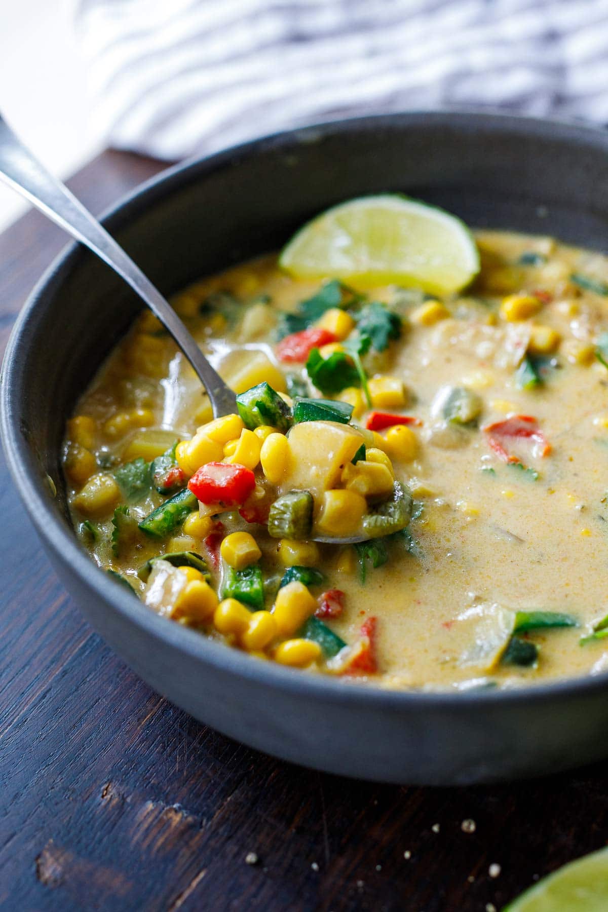 bowl of poblano corn chowder with spoon and lime garnish