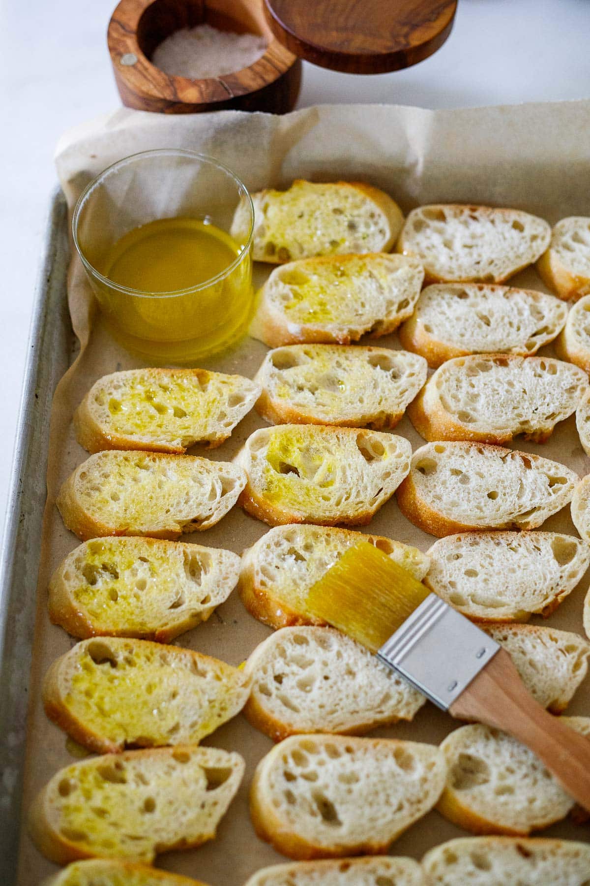 Baguette slices on parchment lined sheet pan with olive oil brush