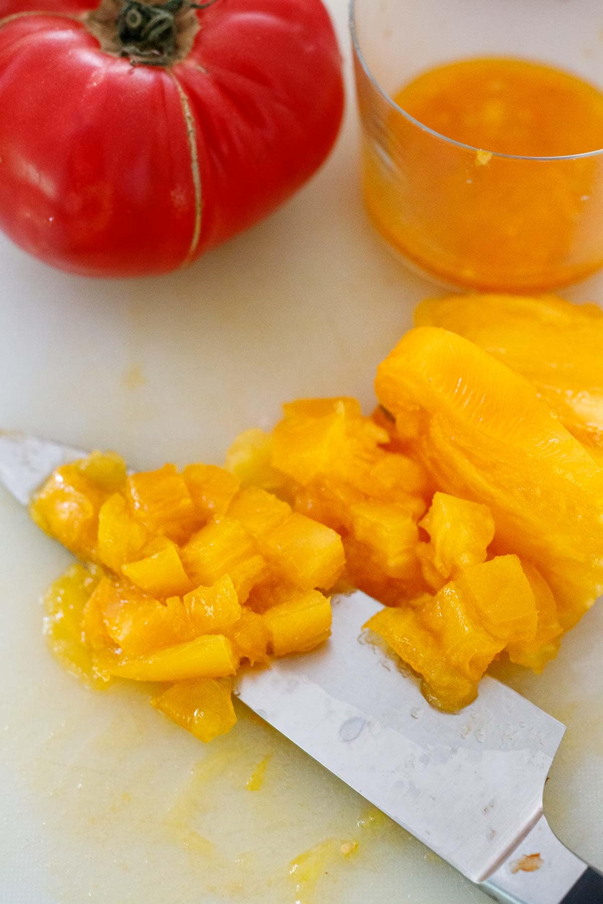 Heirloom tomato diced on cutting board with knife