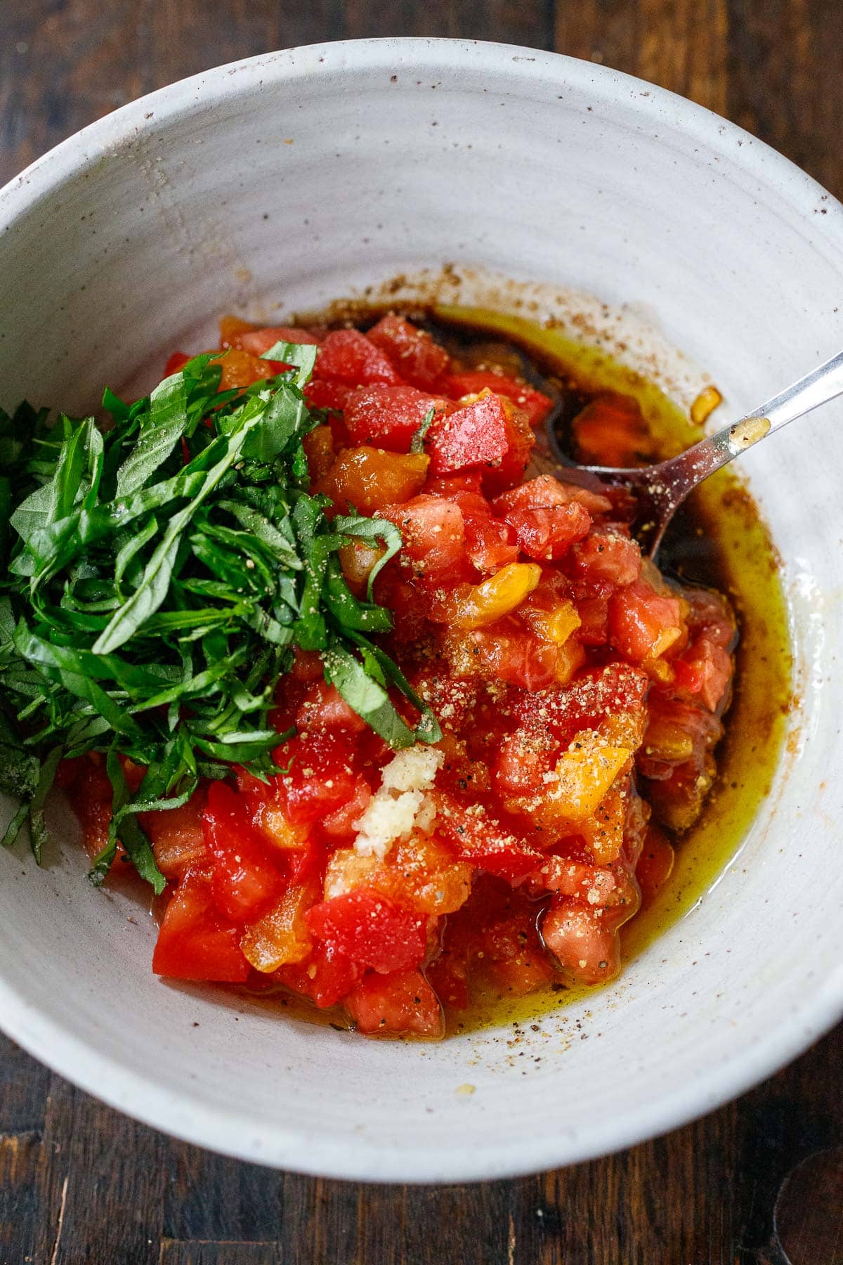 Bruschetta ingredients, tomatoes, basil, garlic, oil and vinegar in bowl