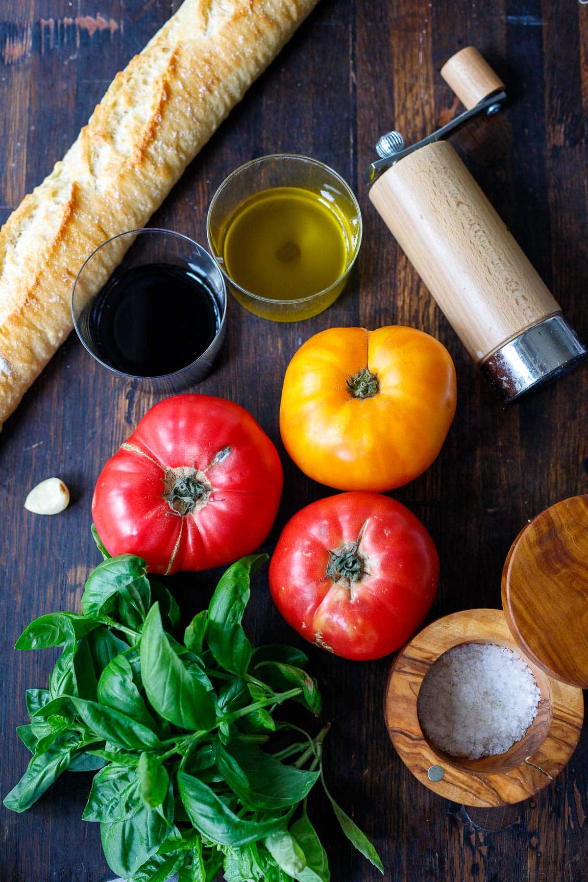 Tomato Bruschetta ingredients on table, heirloom tomatoes, fresh basil, oil and vinegar