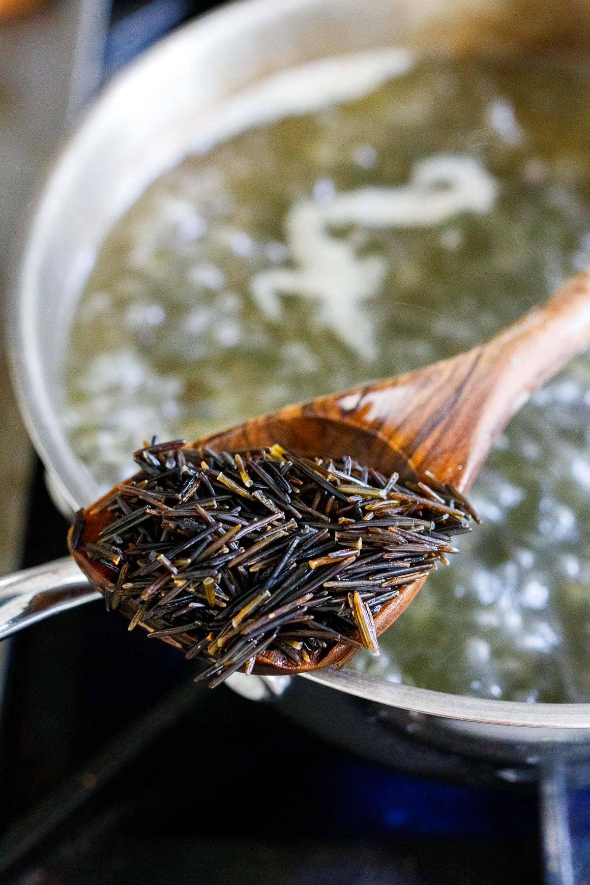 scoop of wild rice over pot of boiling water