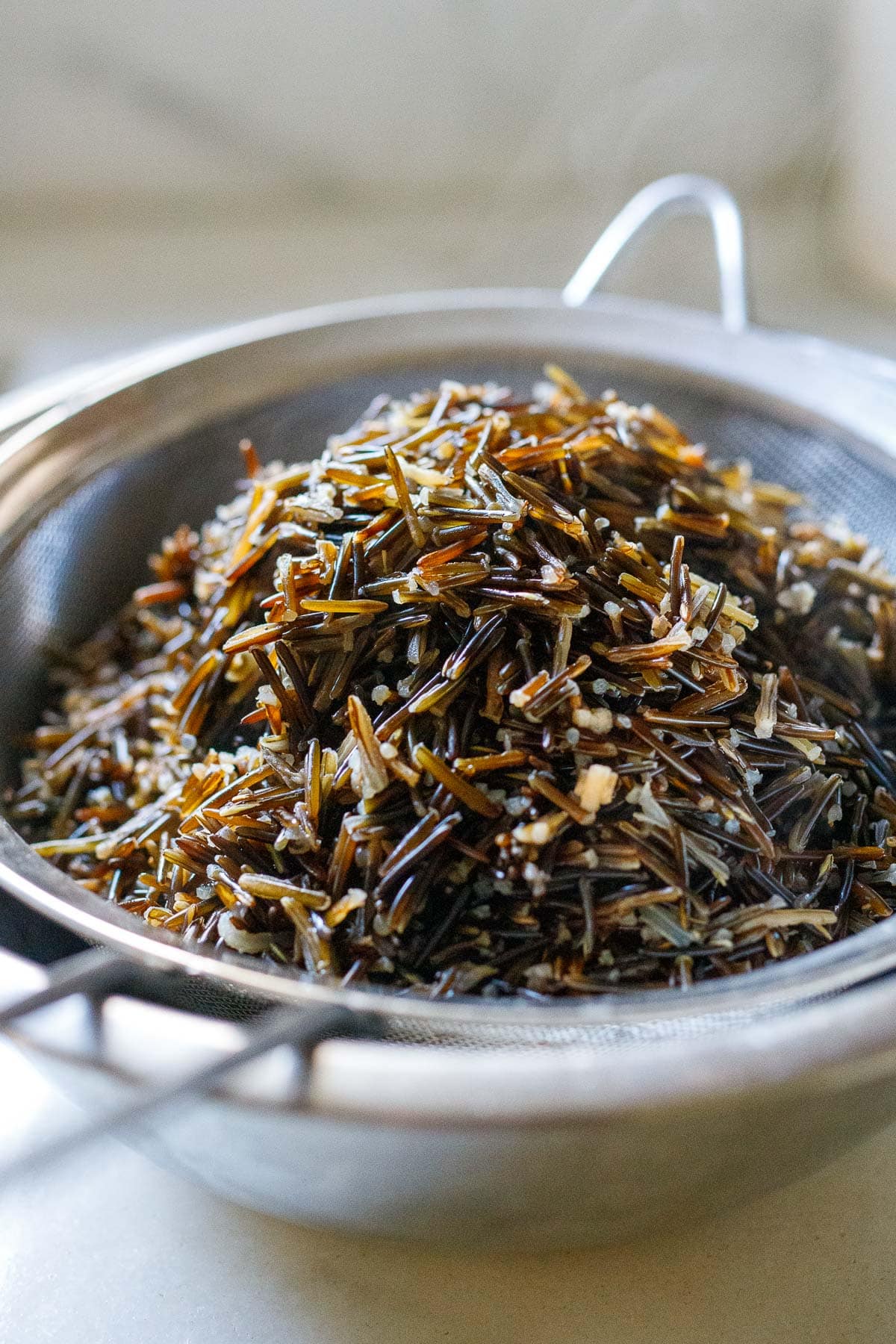 cooked wild rice in fine mesh strainer over bowl