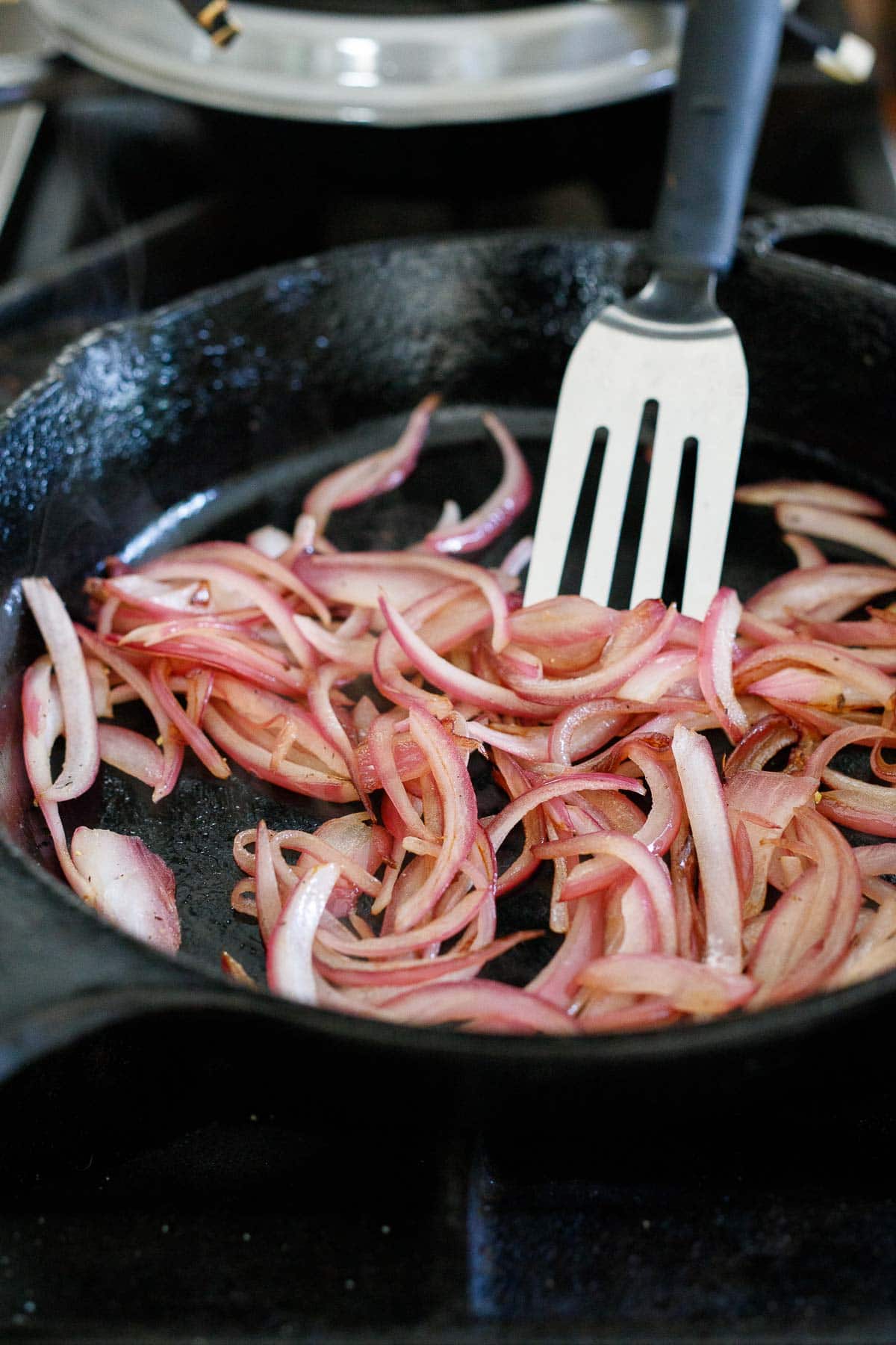 spatula stirring caramelized onions in cast iron skillet