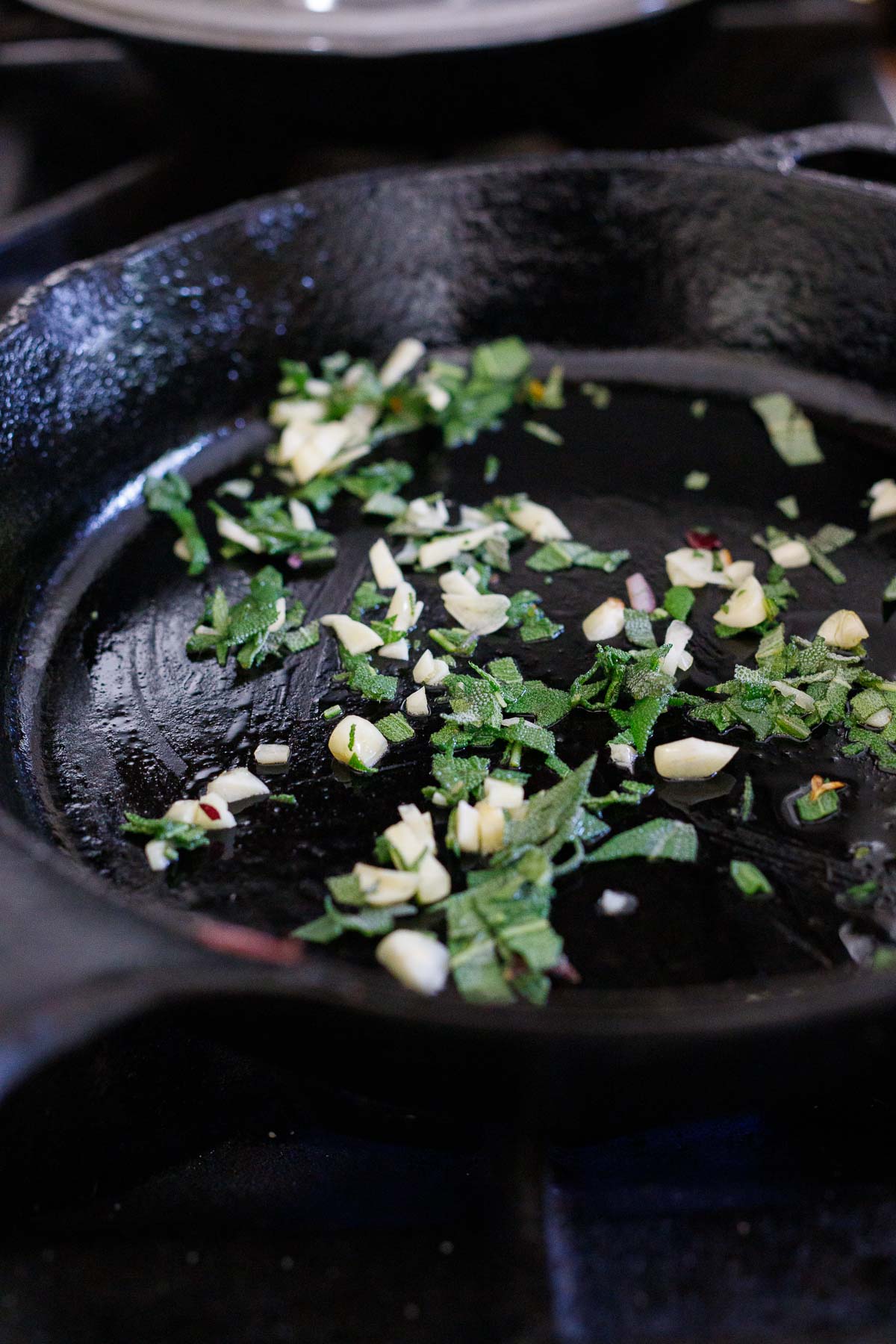garlic and sage cooking in cast iron skillet