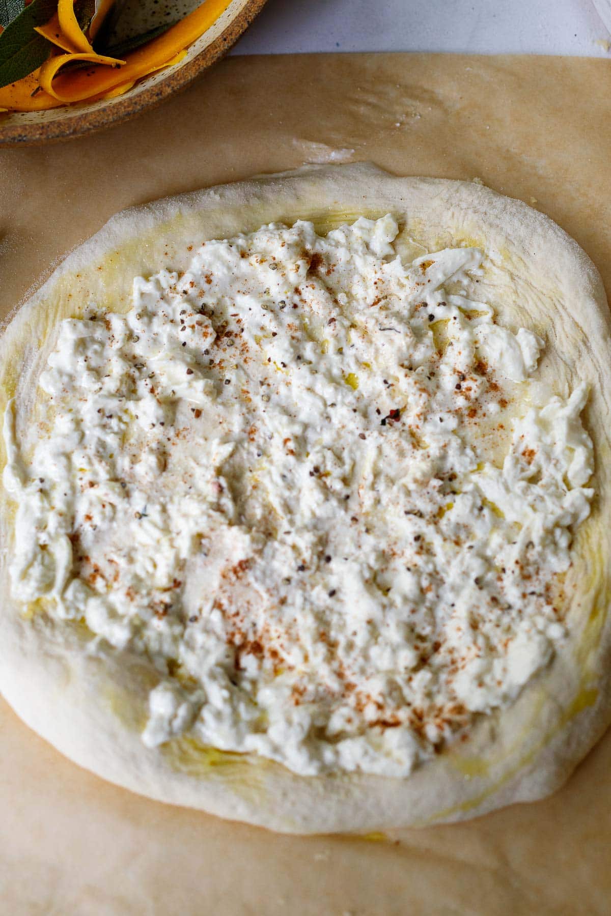 pizza dough rolled out with burrata cheese spread over top