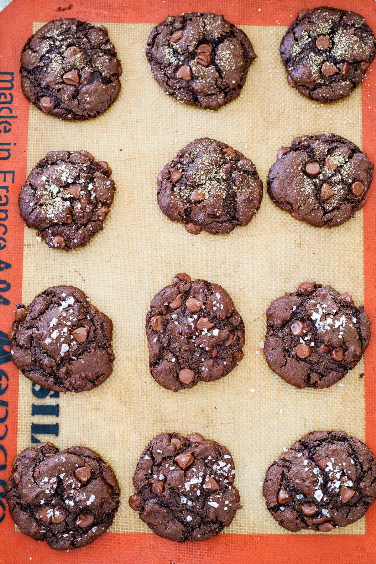 baked double chocolate chip cookies on silpat on baking sheet cooling