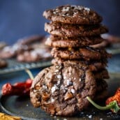 stack of double chocolate chip cookies on plate with chili pepper and cinnamon stick and flaky salt.