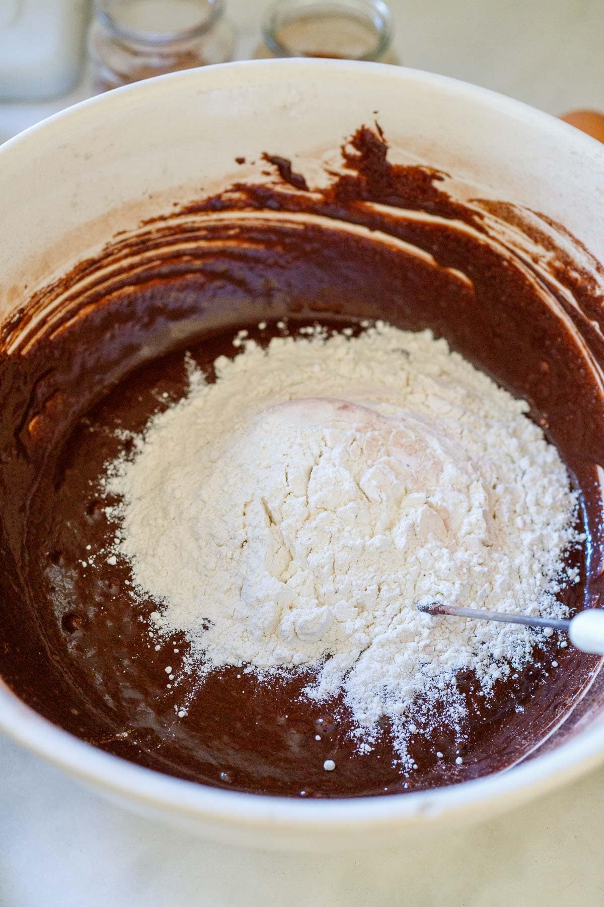 flour being whisked into mixing bowl with wet cocoa mixture