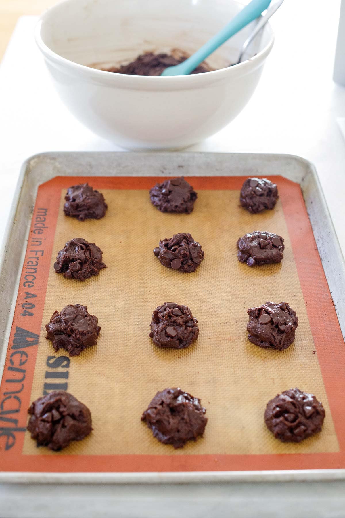 double chocolate chip cookie dough balls spread out evenly on silpat on baking sheet