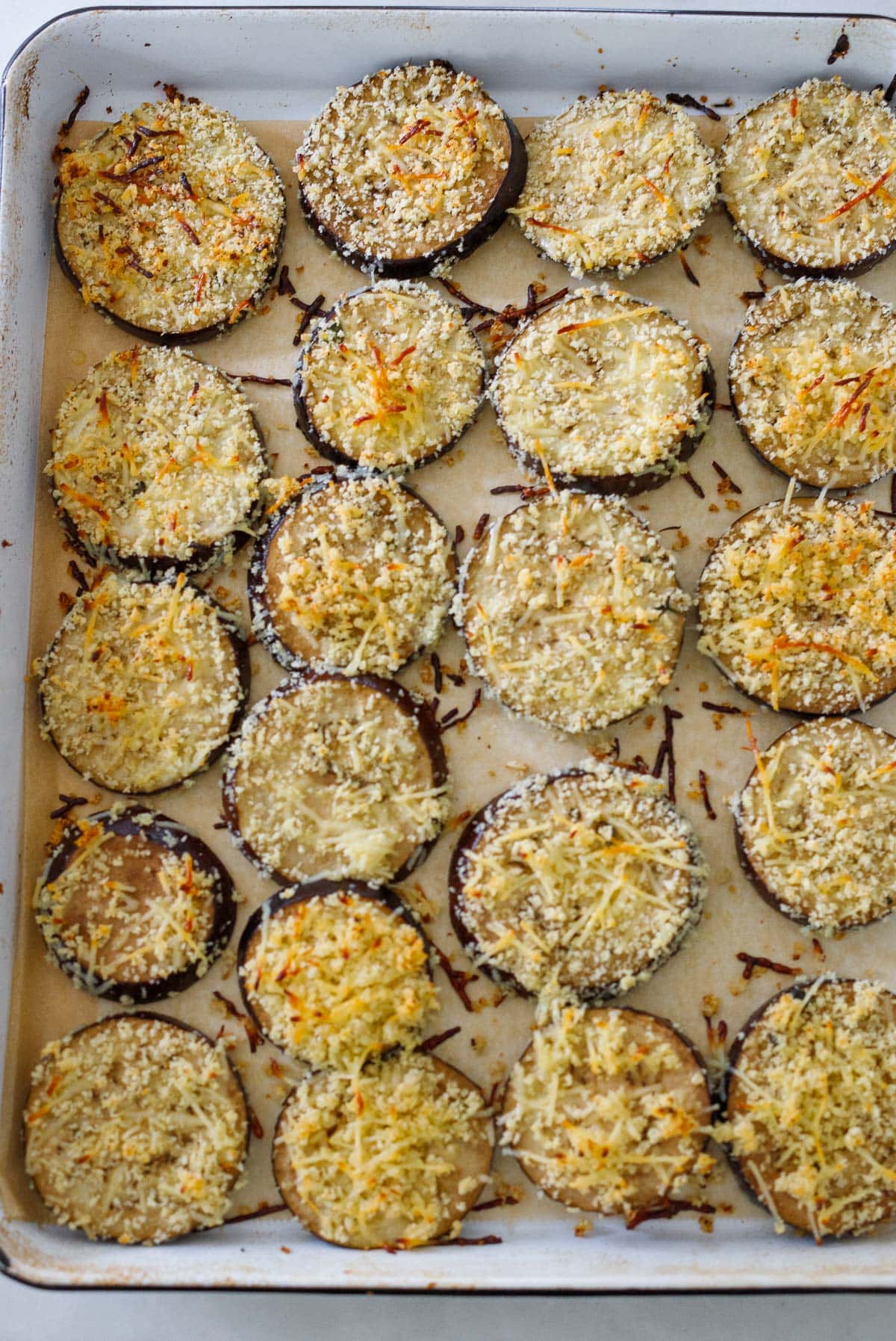 baked eggplant slices on baking sheet with parmesan breadcrumb coating