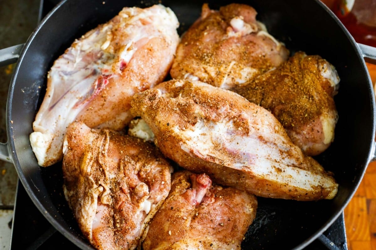 chicken breasts and thighs searing in dutch oven with Baharat spices