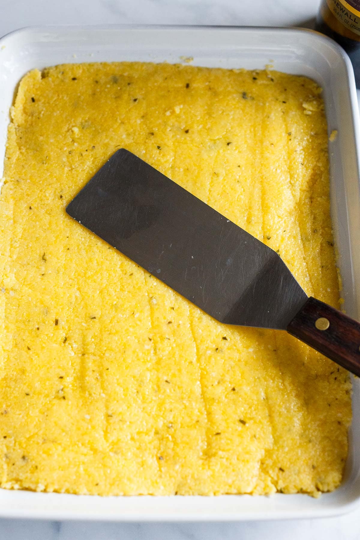 Smooth polenta in a pan with a metal spatula.