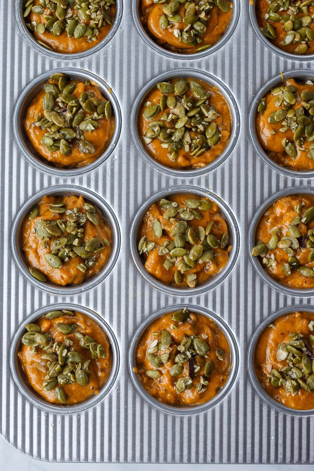 Unbaked pumpkin muffins in muffin tins.