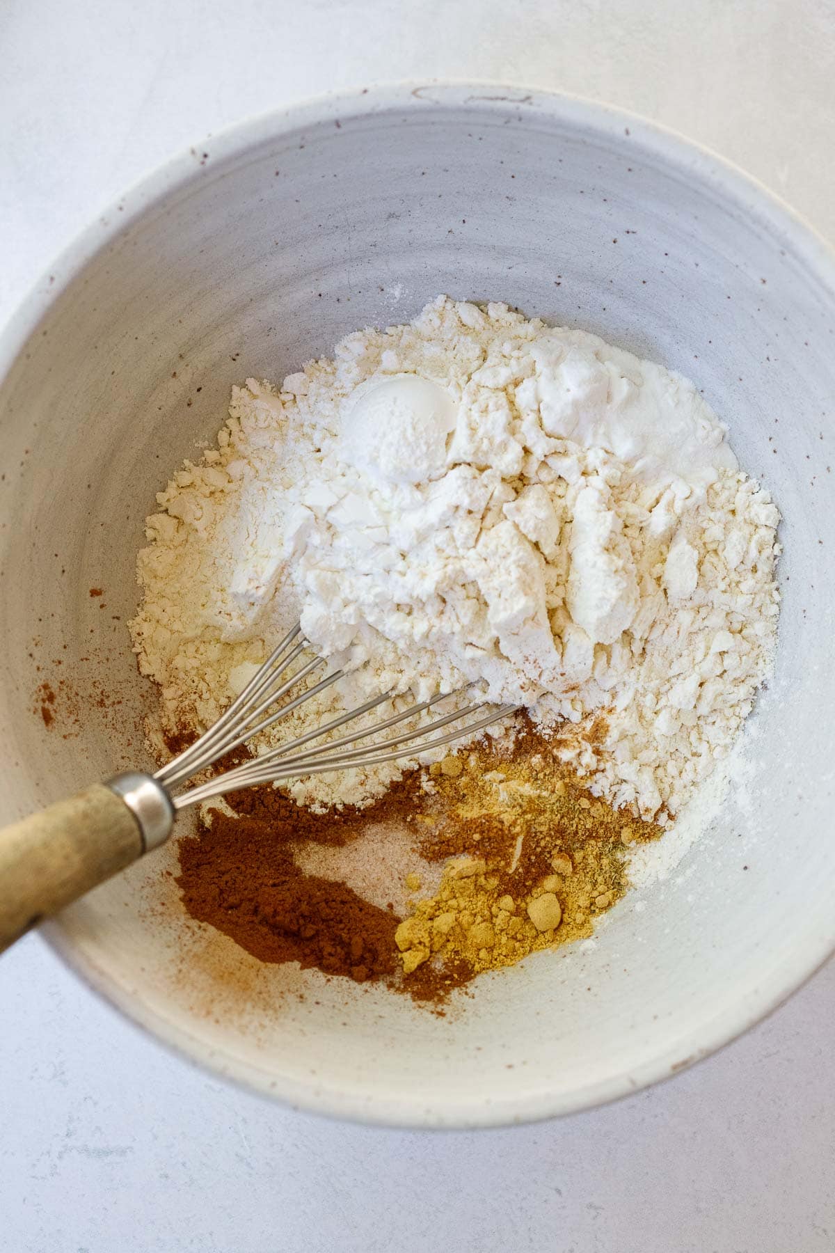 dry ingredients for pumpkin pancakes in bowl with whisk
