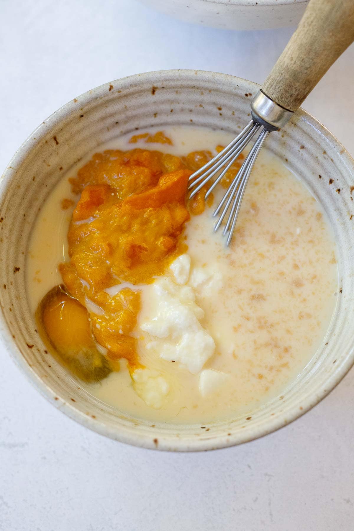 wet ingredients for pumpkin pancakes in bowl with whisk