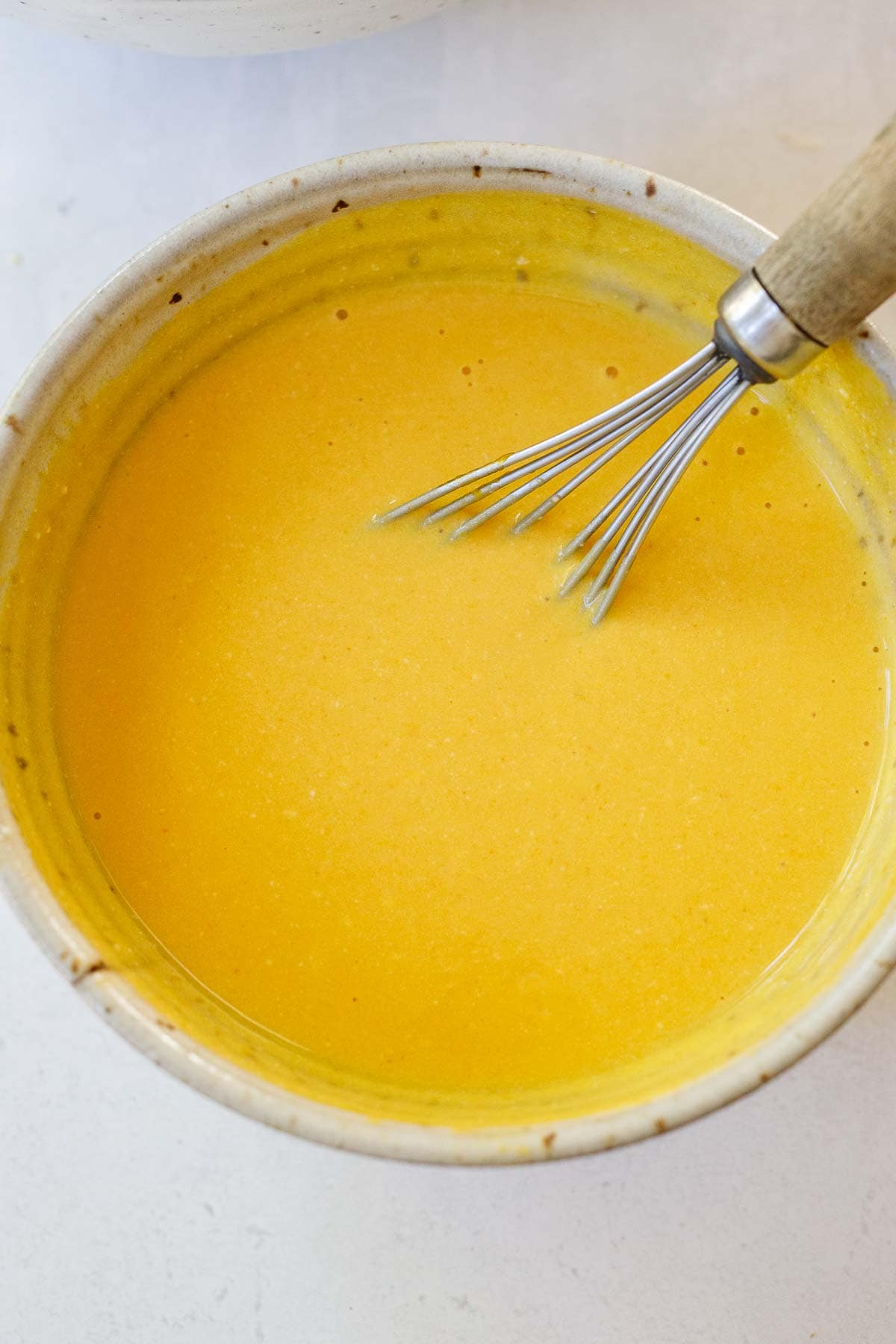 wet ingredients for pumpkin pancakes whisked together in bowl with whisk