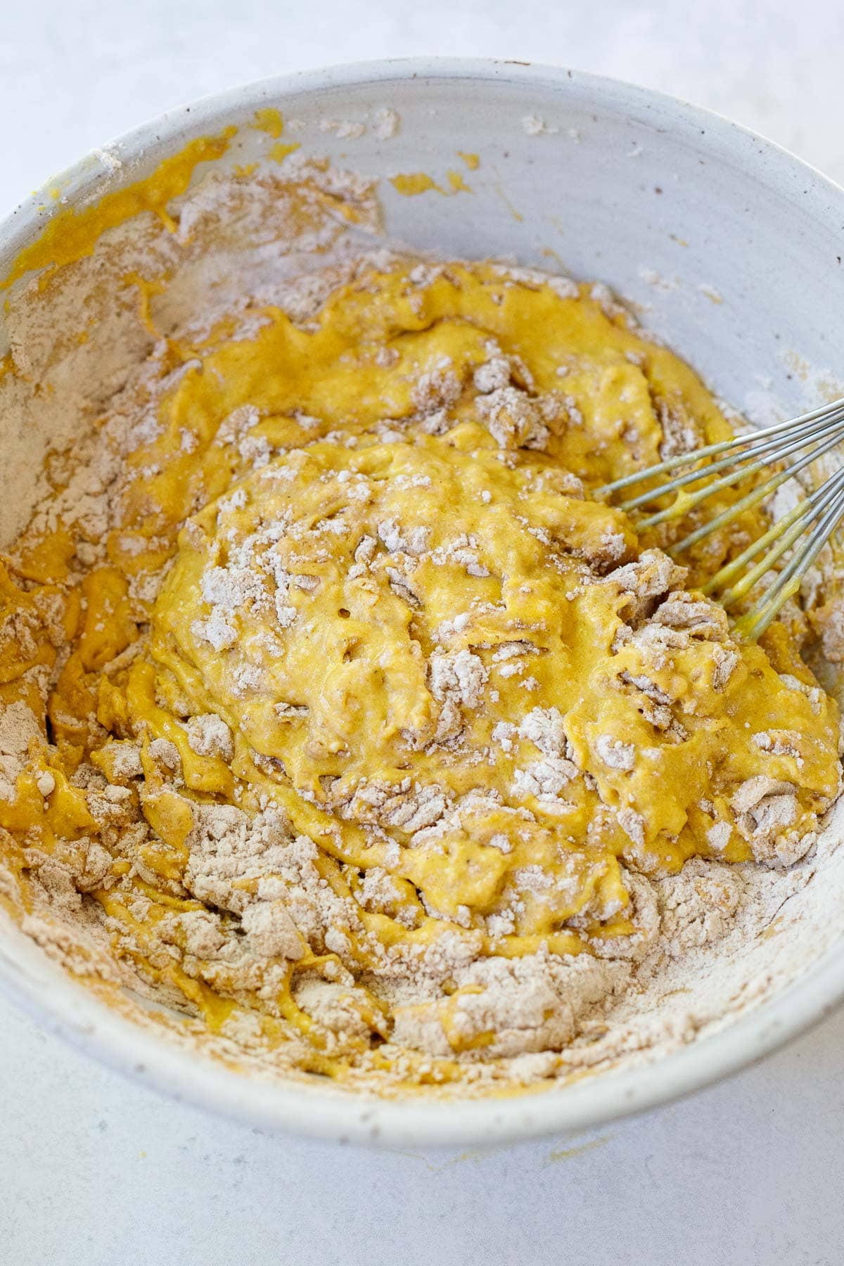 wet and dry ingredients for pumpkin pancakes folded together in bowl not fully mixed