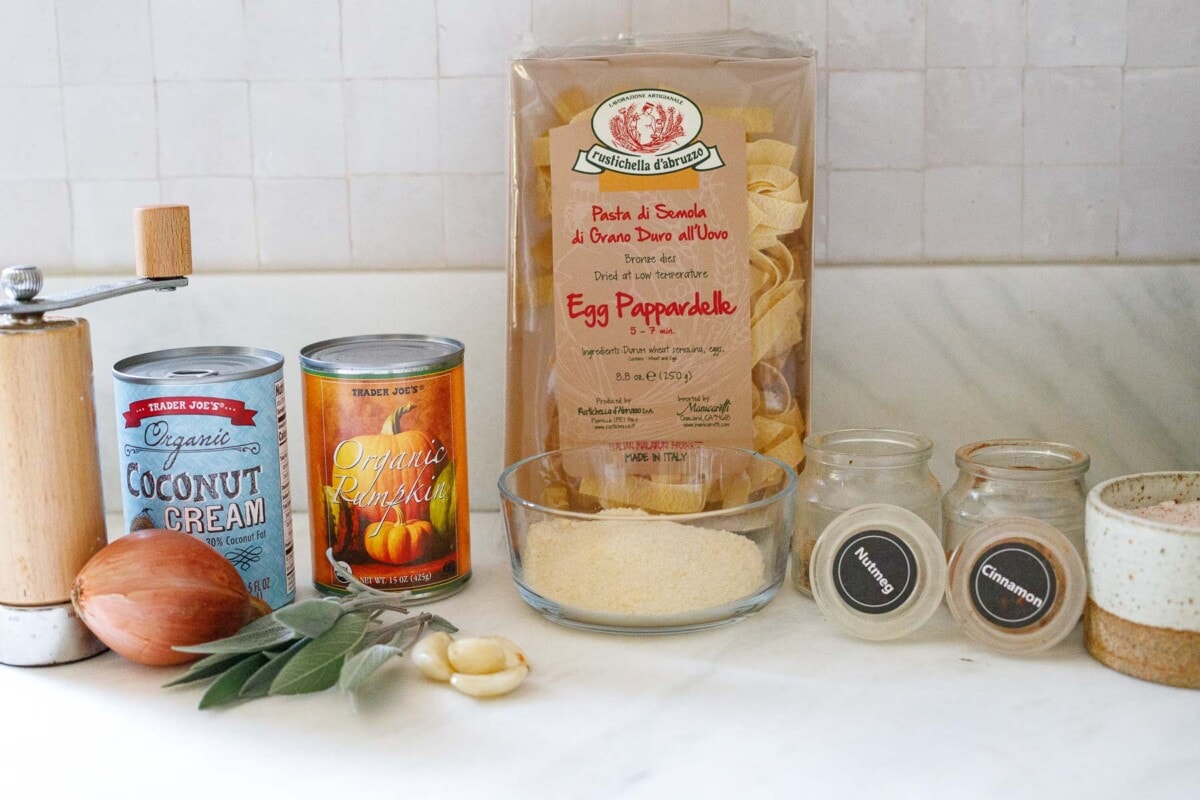 ingredients displayed on countertop for making pumpkin pasta, pumpkin puree, pasta, coconut cream, shallot, sage, garlic