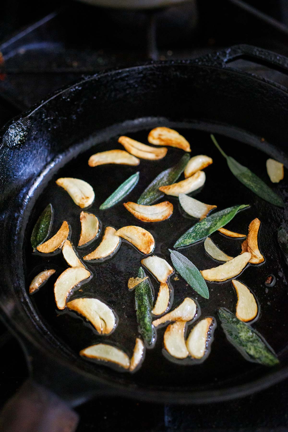 frying garlic chips and sage leaves in cast iron skillet