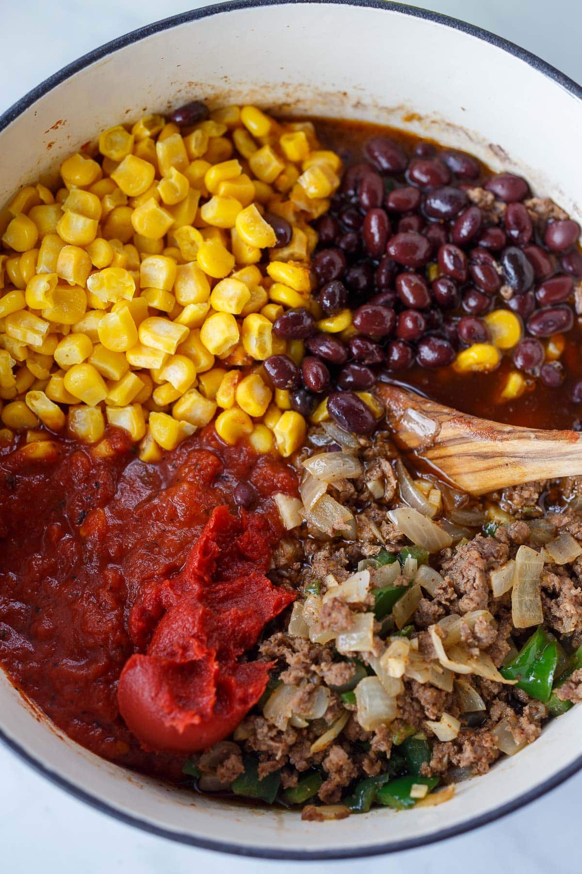 Corn, beans, tomatoes and meat in a soup pot for Taco Soup.