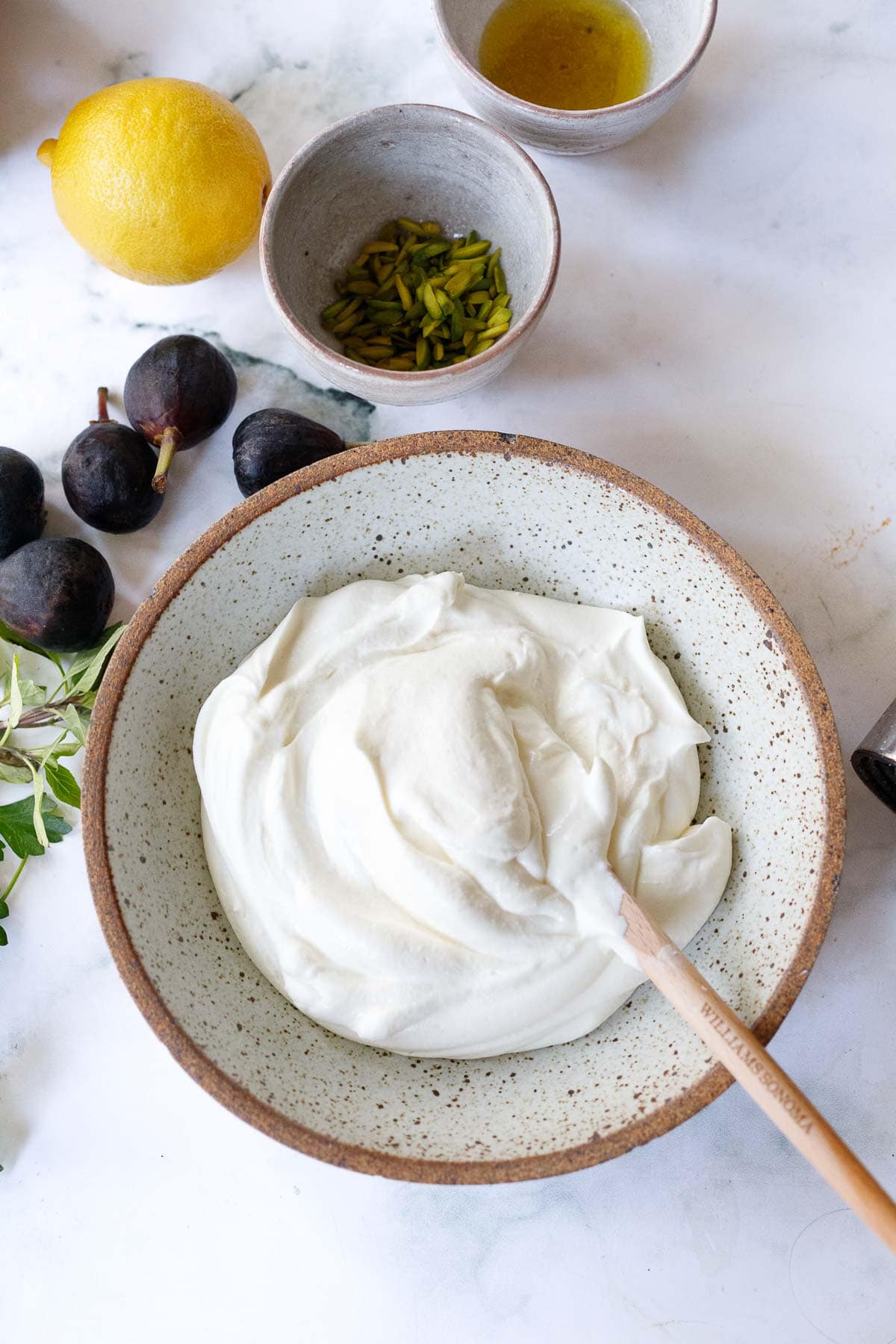 ceramic serving bowl with whipped ricotta and spatula, toppings on table beside