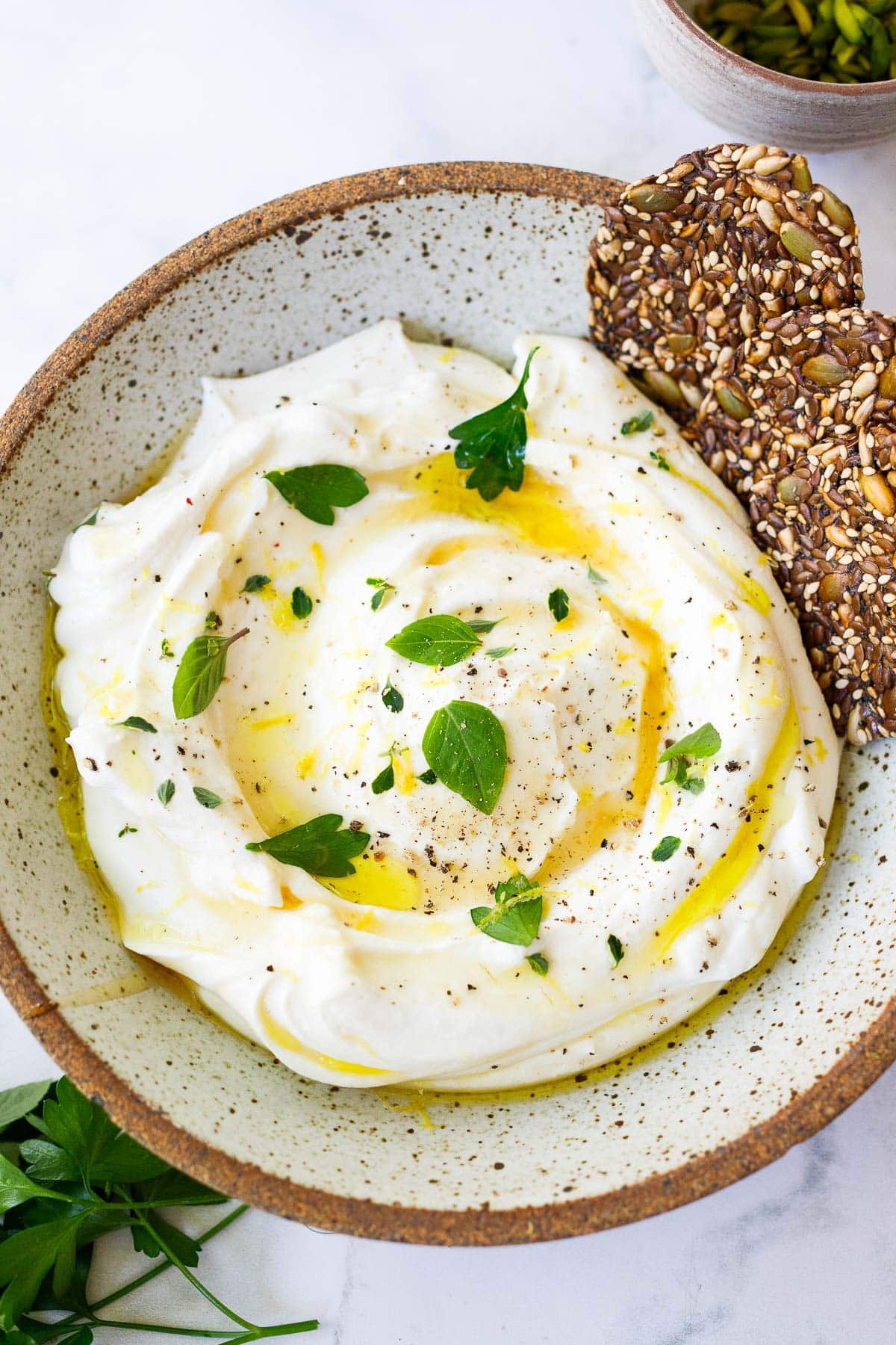 bowl of whipped ricotta with lemon zest, fresh herbs, honey, and crackers