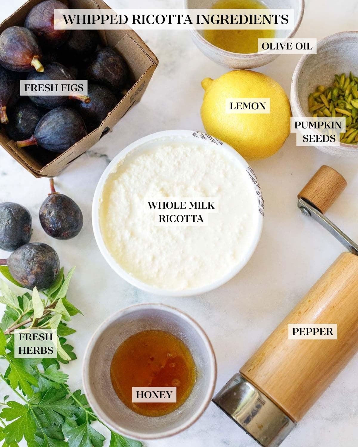 ingredients for whipped ricotta on table, ricotta cheese, lemon, honey, pistachios, figs, herbs