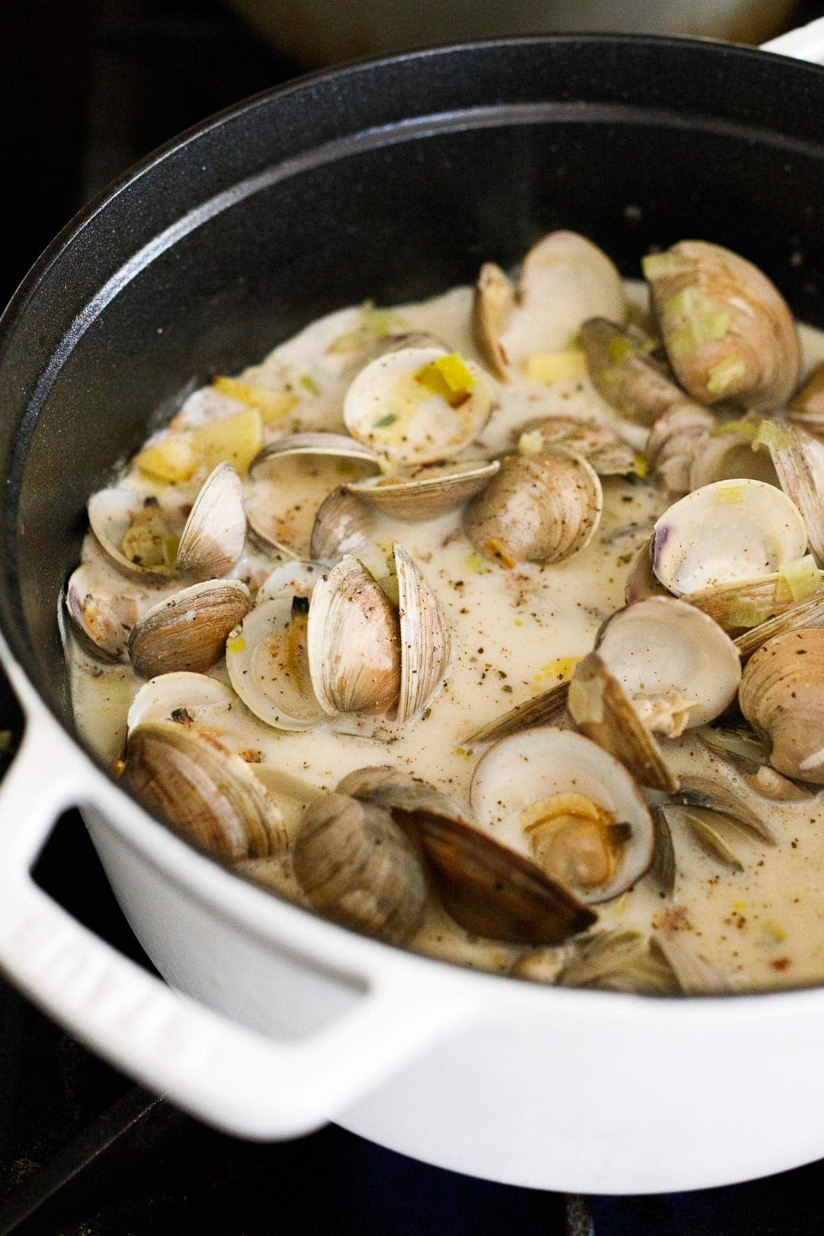clams in shells added to soup pot with chowder