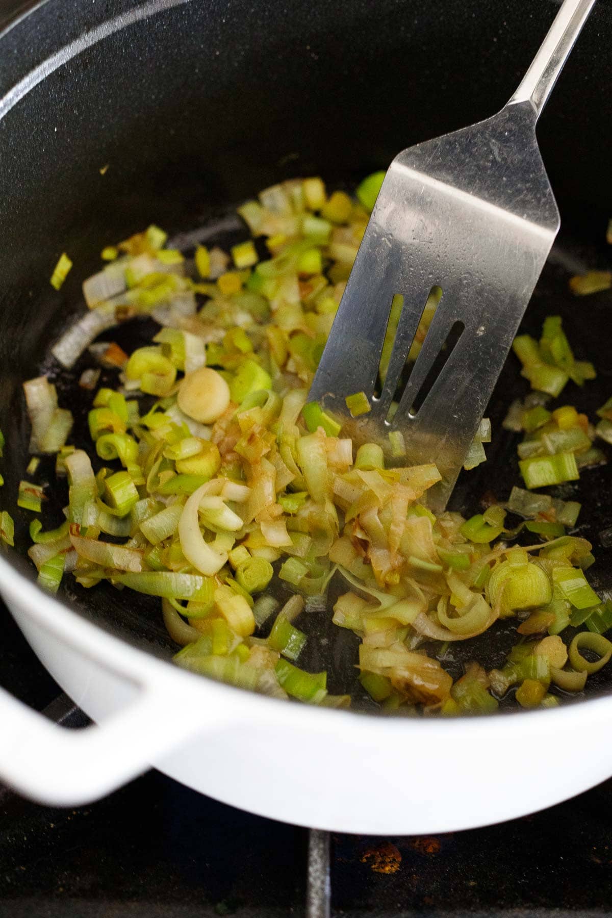 leeks cooking in pot with spatula