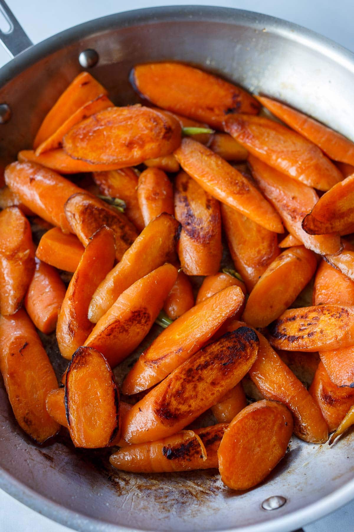 Carrot slices searing in a pan for glazed carrots.
