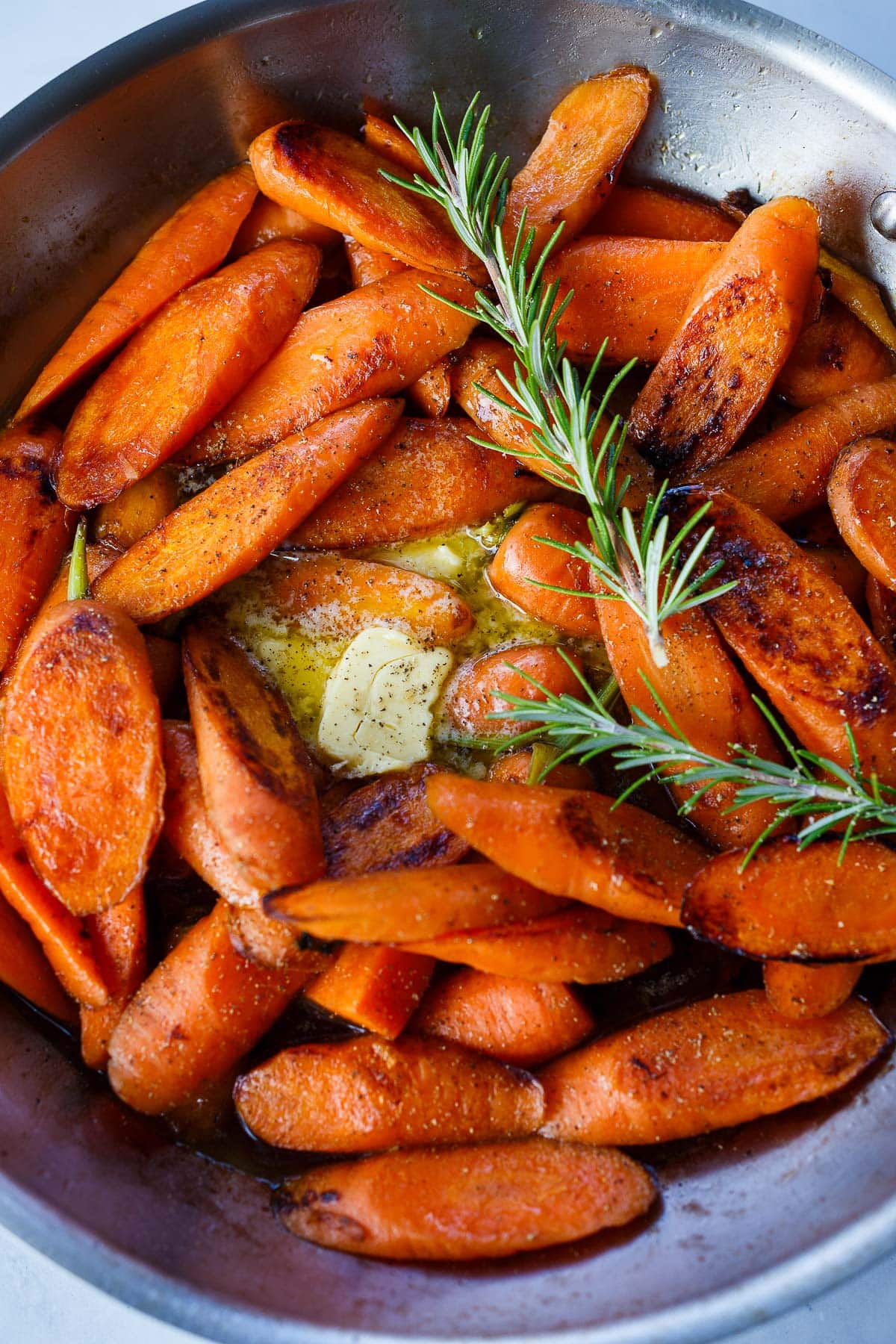 Carrots, butter, rosemary in a pan for glazed carrots.