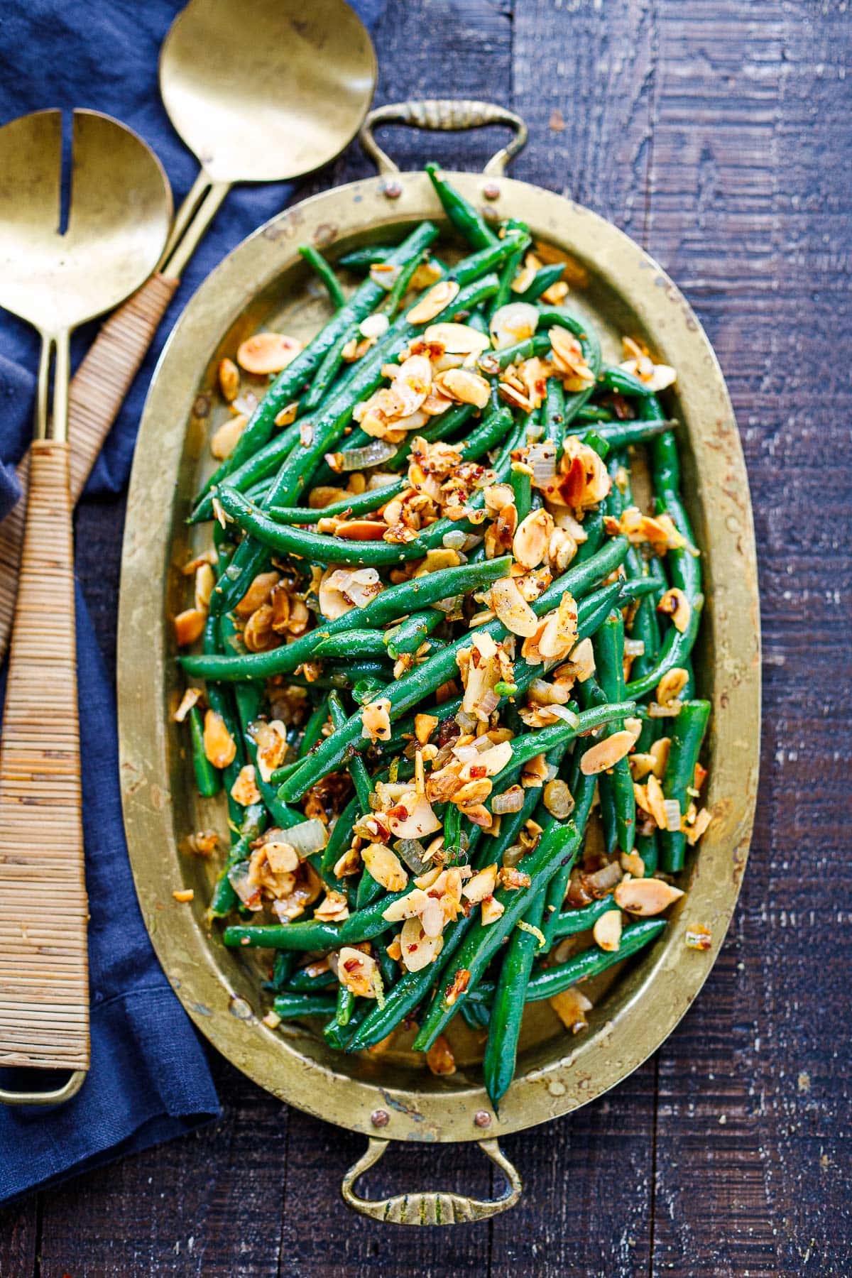 green beans almondine in serving platter with sliced toasted almonds and chili flakes on top