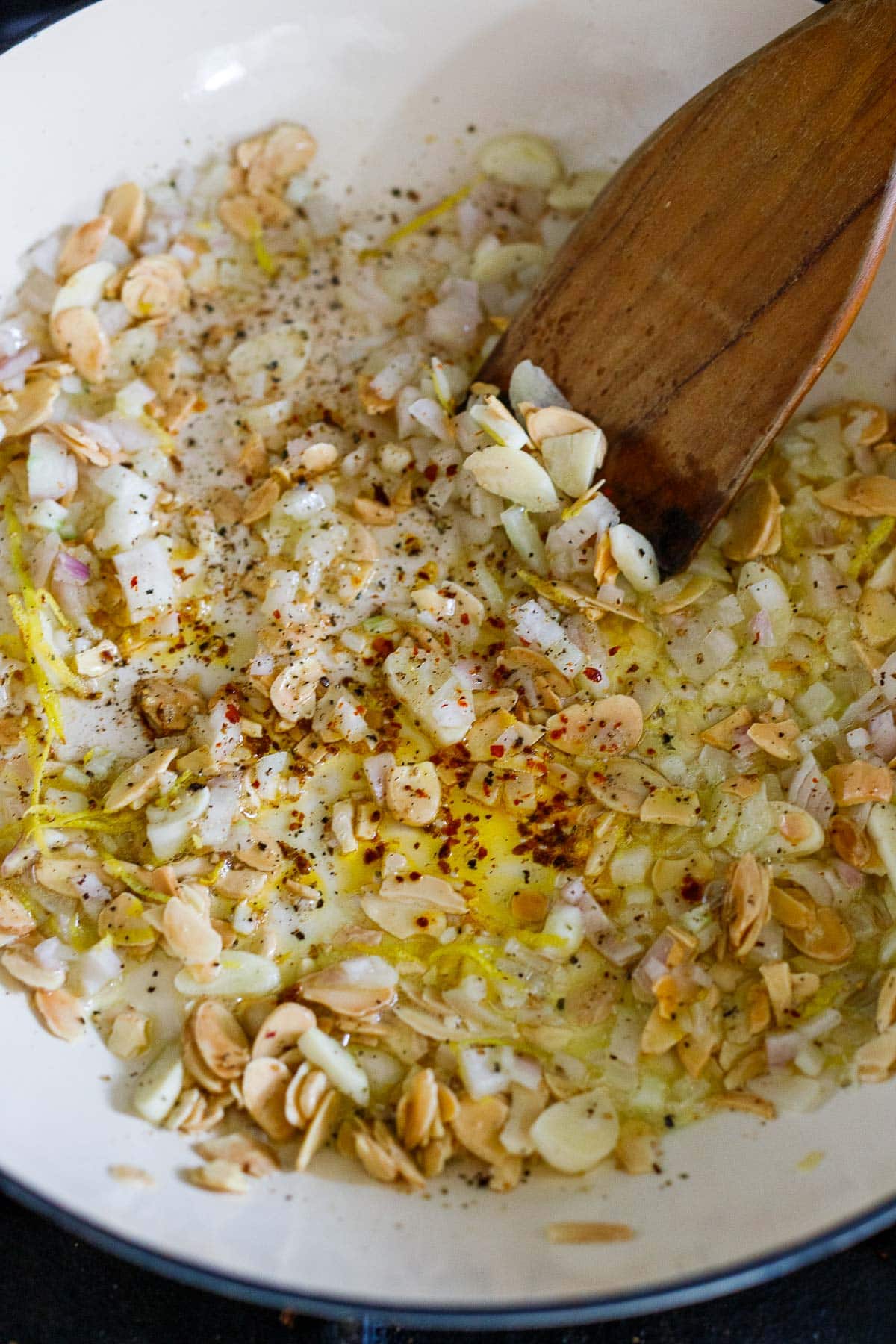 toasted almonds in saute pan with chopped shallots, sliced garlic, red pepper flakes, and black pepper