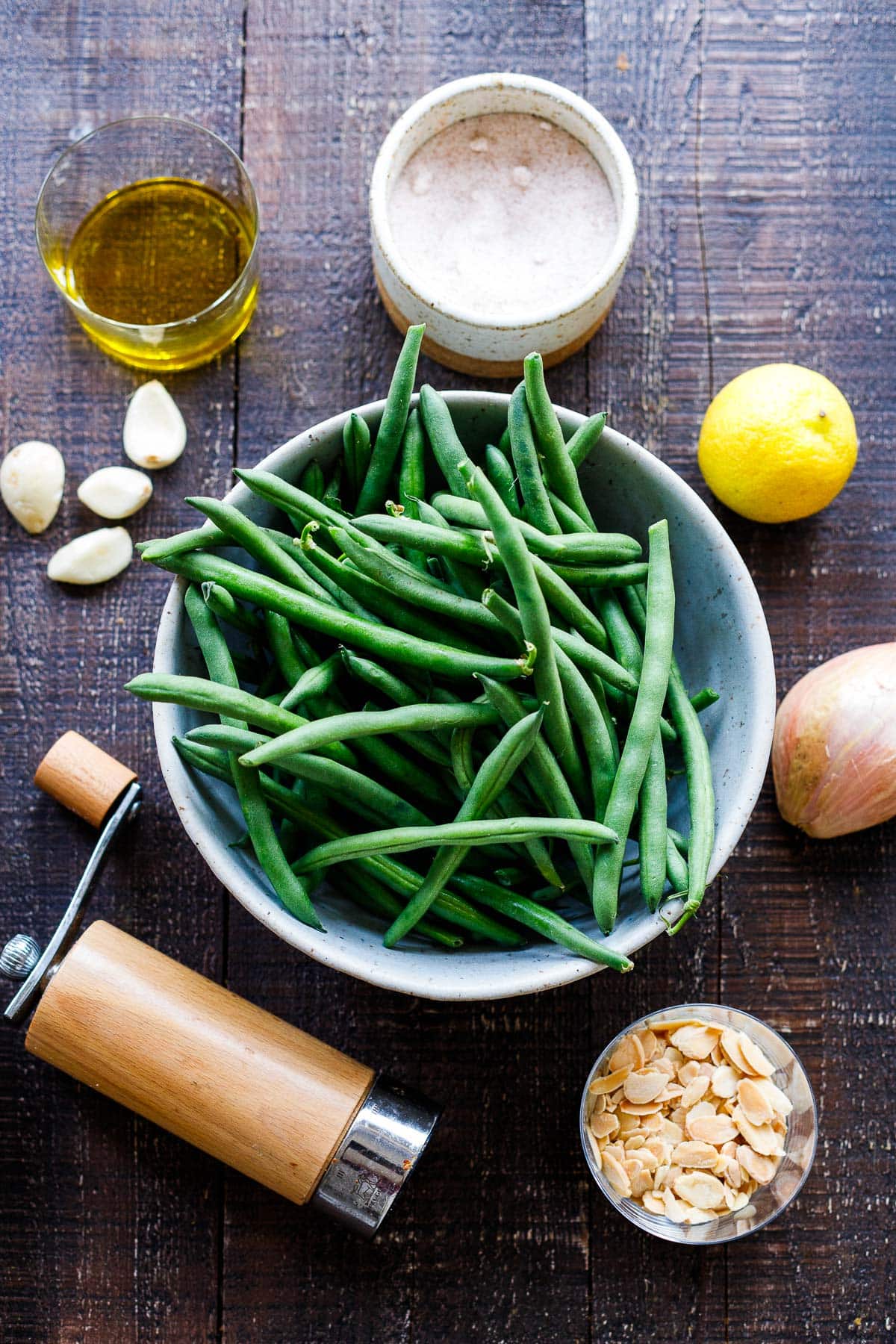 ingredients laid out for green beans almondine - green beans, lemon, shallot, salt, pepper, garlic, oil, sliced almonds