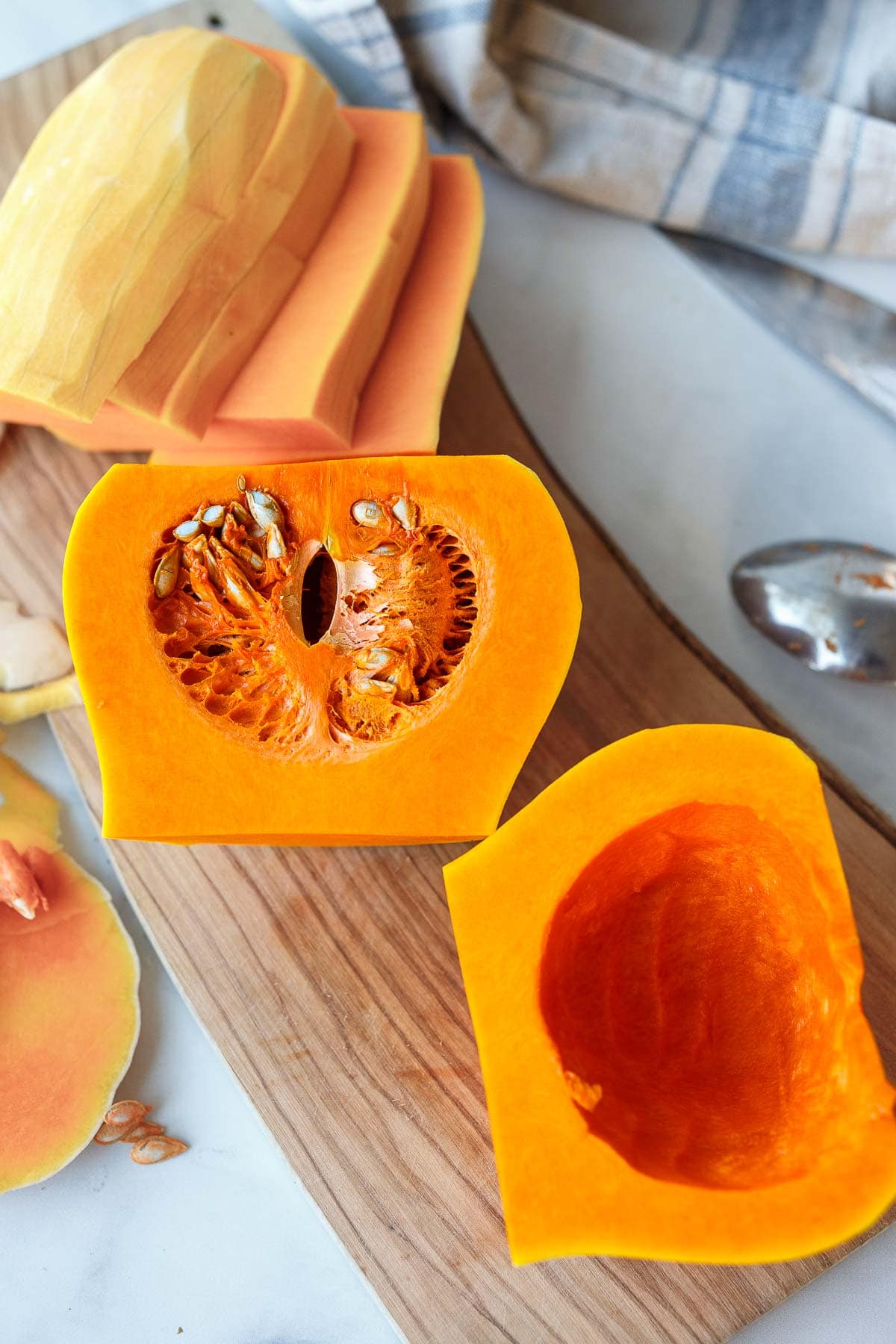 peeled butternut squash cut in half, showing one half with seeds and one with them scooped out