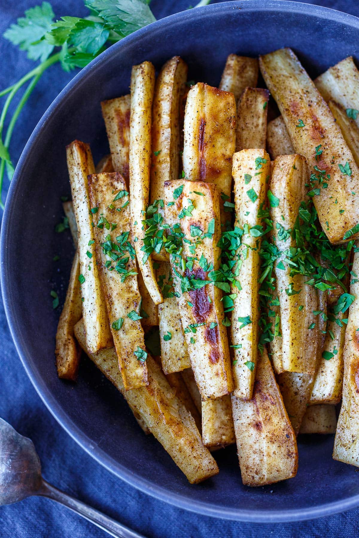serving dish with roasted parsnips, seasoned well, garnished with minced fresh parsley