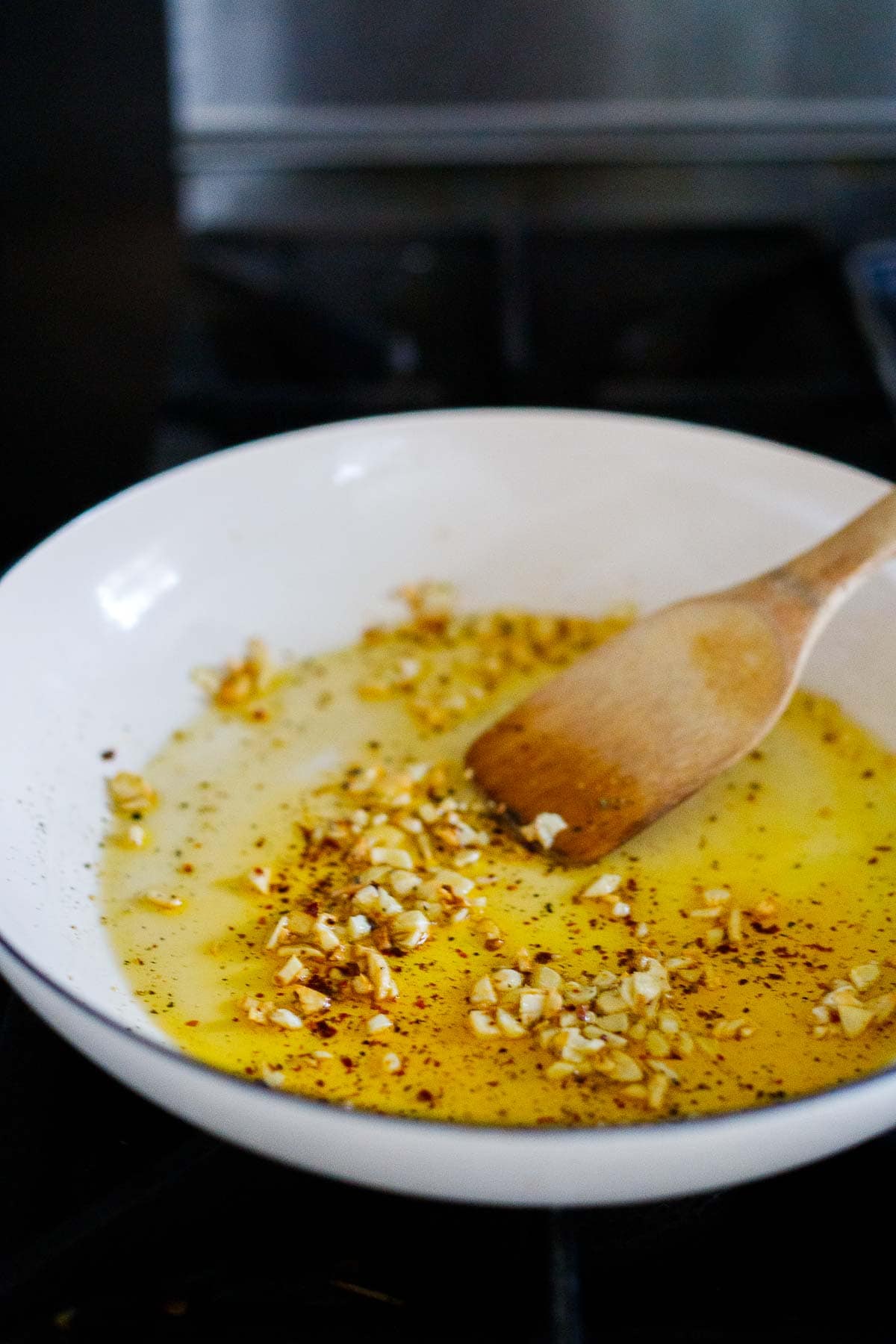 garlic and spices in oil in skillet with wood spatula