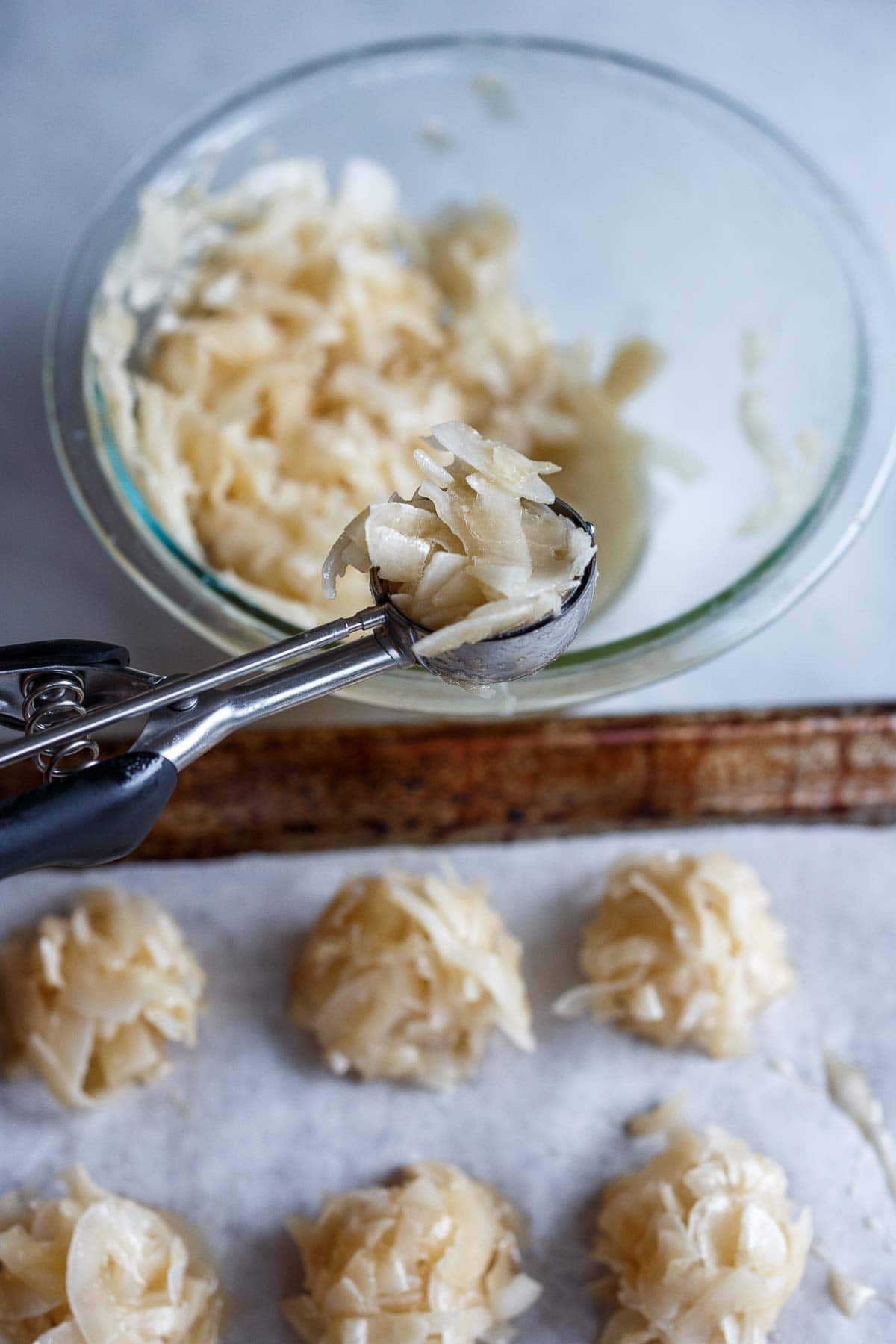 Scooping macrons onto a sheet pan.