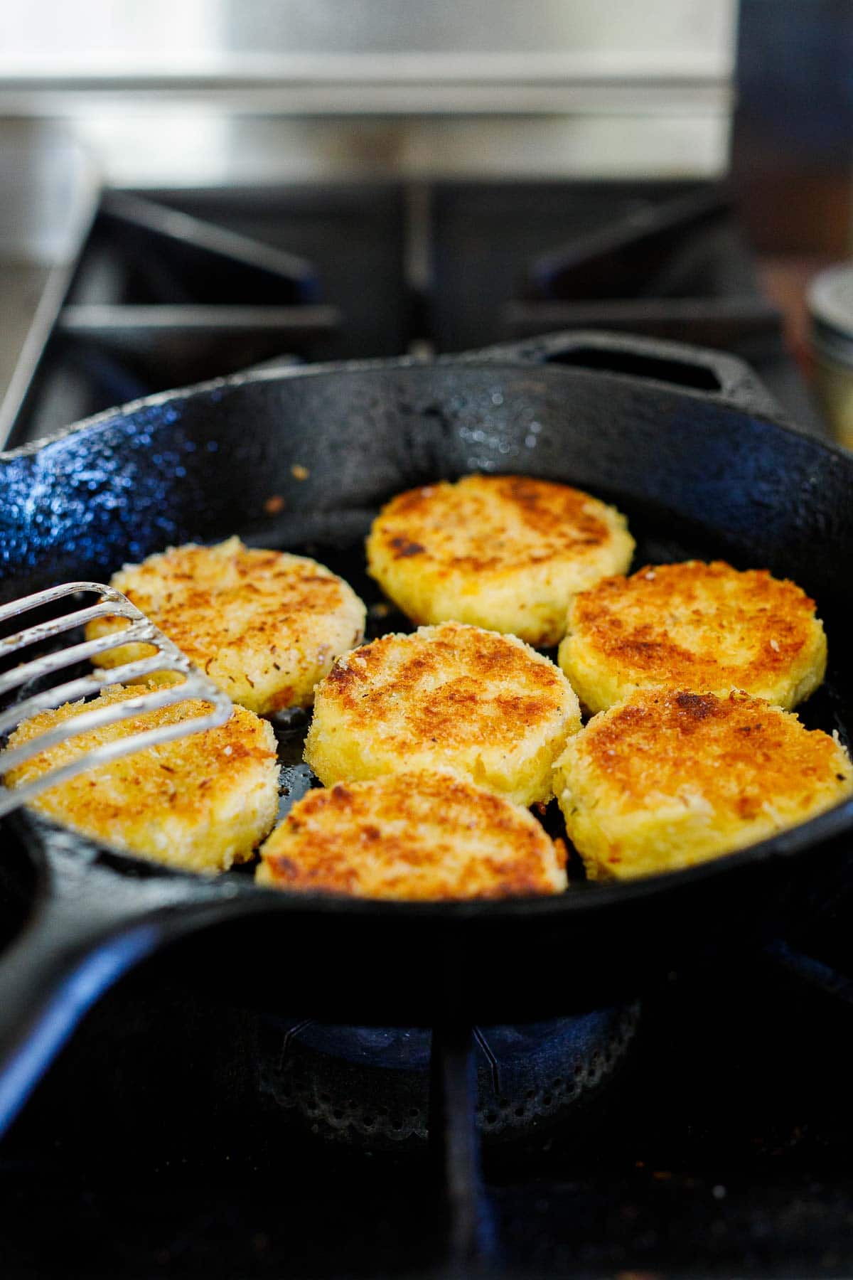 mashed potato cakes frying in cast iron skillet