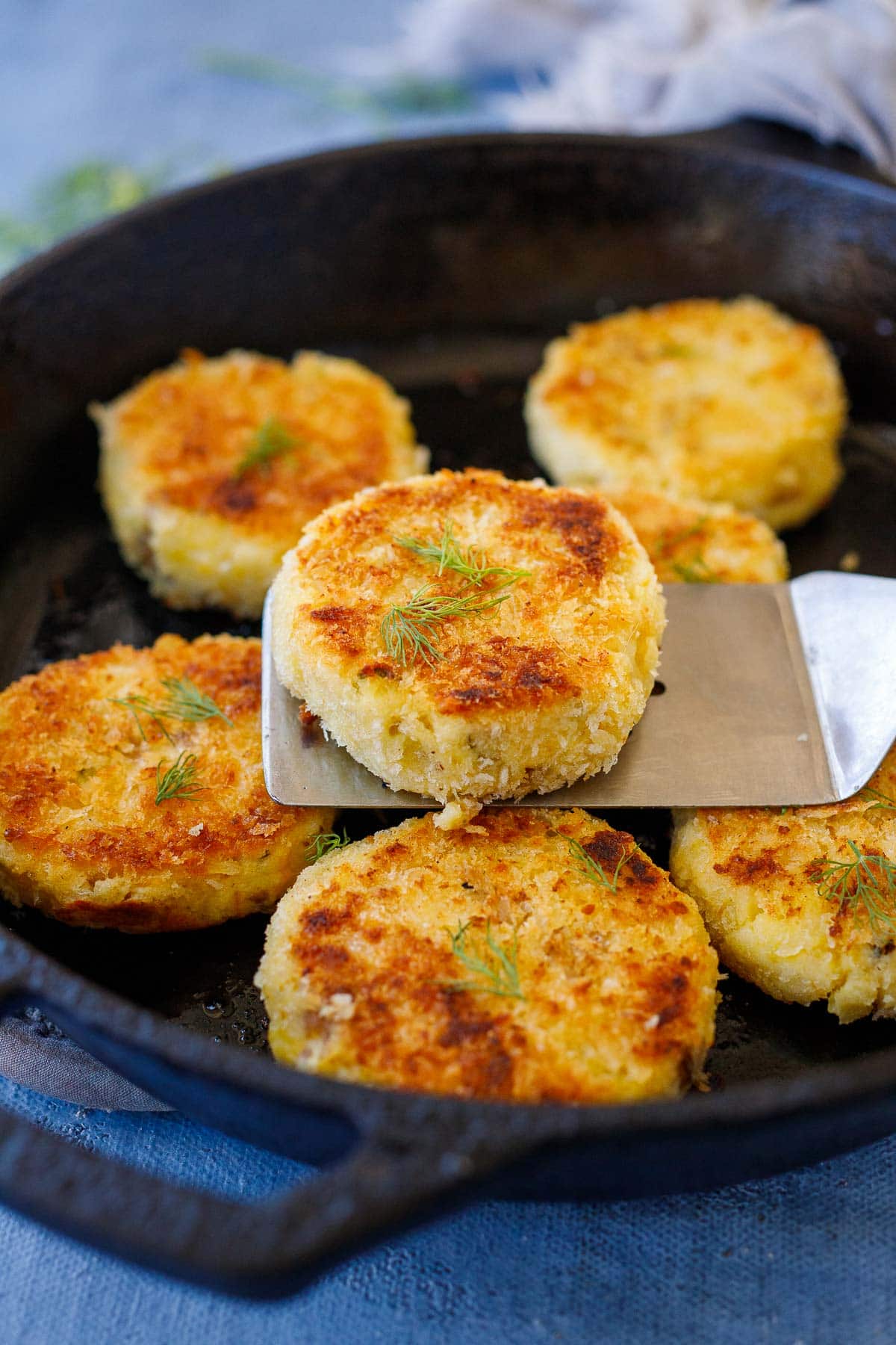 spatula holding up a mashed potato cake garnished with fresh dill