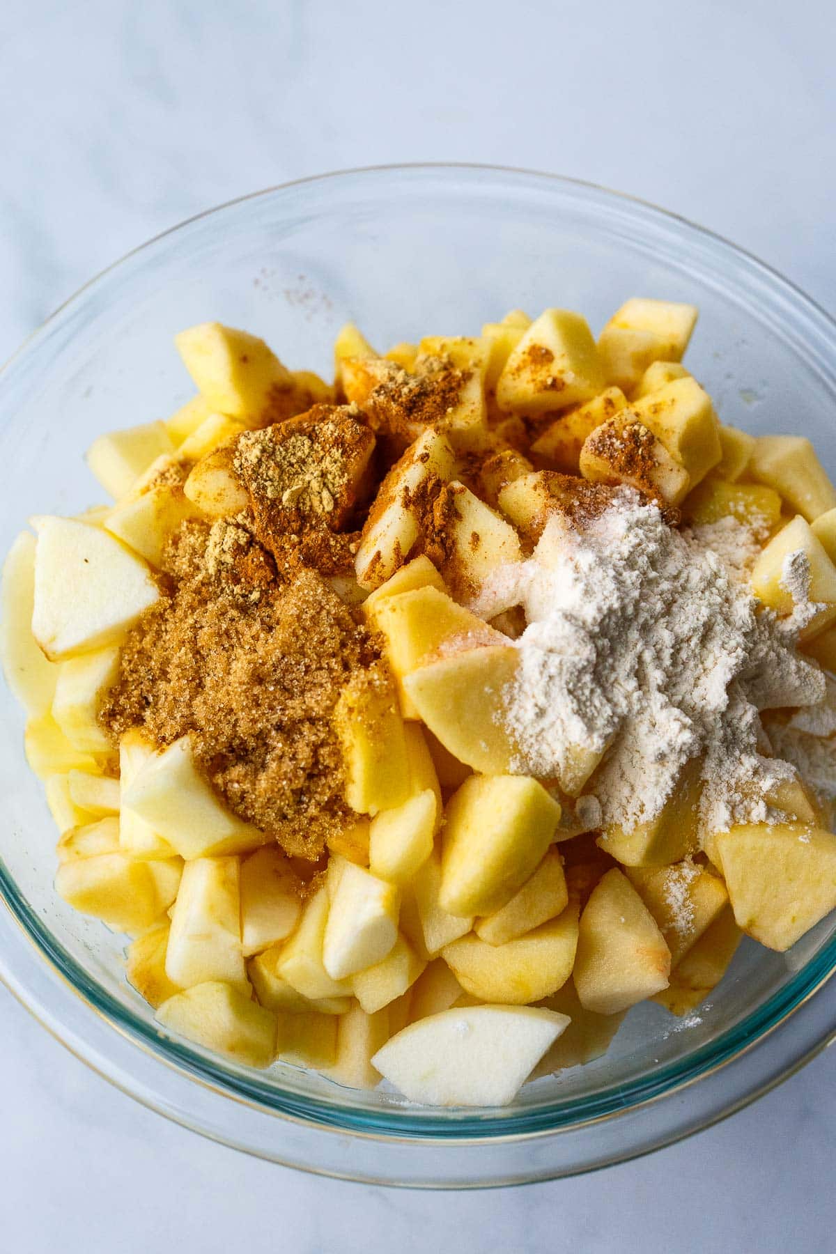 chopped apples in mixing bowl with spices and flour for apple crisp