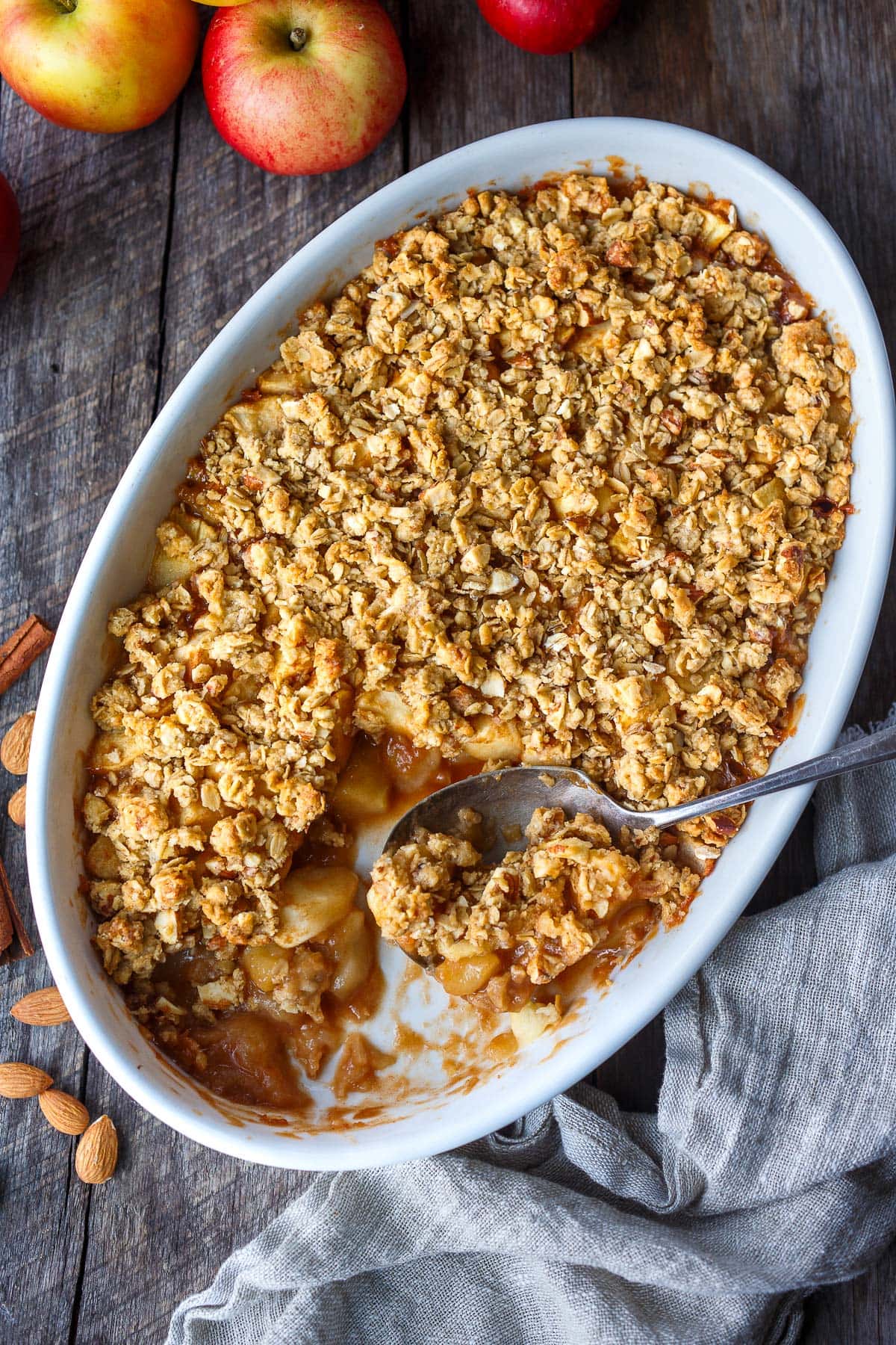 baked apple crisp in baking dish with spoon scooping bite out