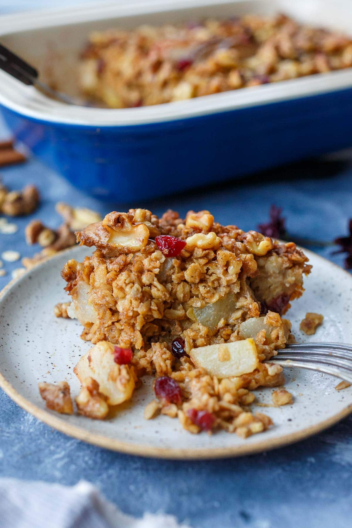 piece of baked oatmeal on plate with pears, dried cranberries, walnuts
